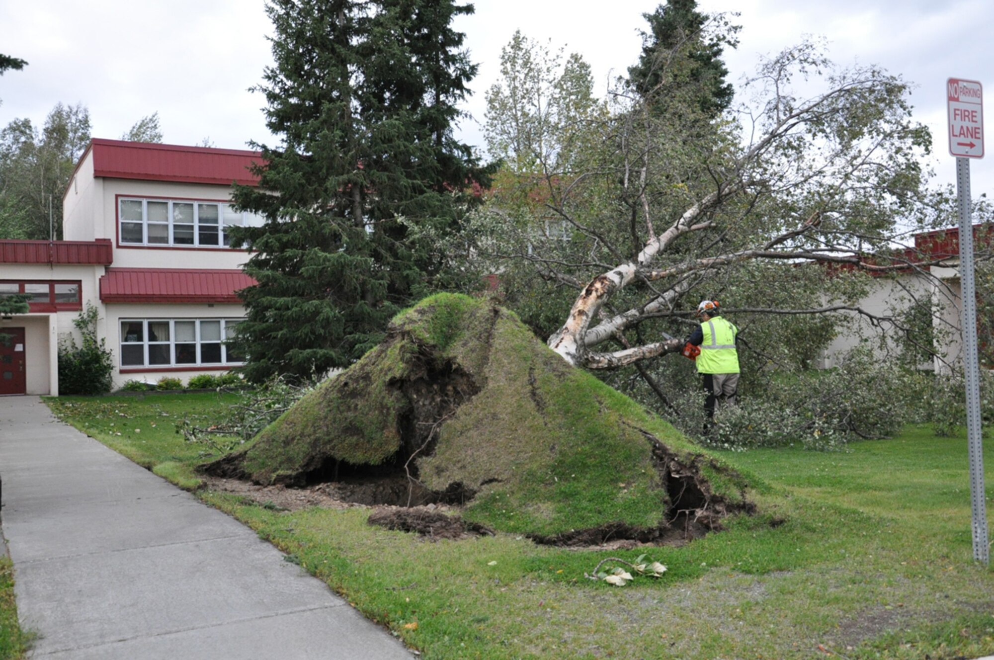 A SHAW contractor cuts up a fallen tree in front of the Soldiers' Chapel. An arctic storm wreaked havoc on Joint Base Elmendorf-Richardson  Sept. 4 and 5 causing widespread damage as well as power and water outages. The Richardson-side of the installation was the hardest hit; uprooting dozens of the trees and scattering debris all around. The arctic storm, which blow up from the Bering Sea, brought winds up to 100 mph according to the National Weather Service. (U.S. Air Force photo by Bob Hall/JBER Public Affairs)