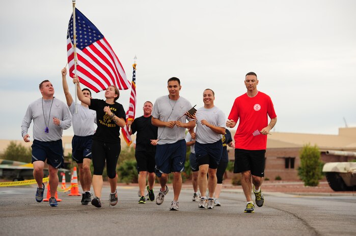 Airmen from the 757th Maintenance Squadron run with the American flag during the 9/11 Old Glory Challenge Sept. 11, 2013, at Nellis Air Force Base, Nev. The 9/11 Old Glory Challenge is an event held in tribute to those who lost their lives during the terrorist attack on Sept. 11. Units from Nellis AFB ran in 30 minute increments around Freedom Park with the Flag from 6 a.m. to 4:30 p.m. (U.S. Air Force photo by Staff Sgt. Michael Charles) 