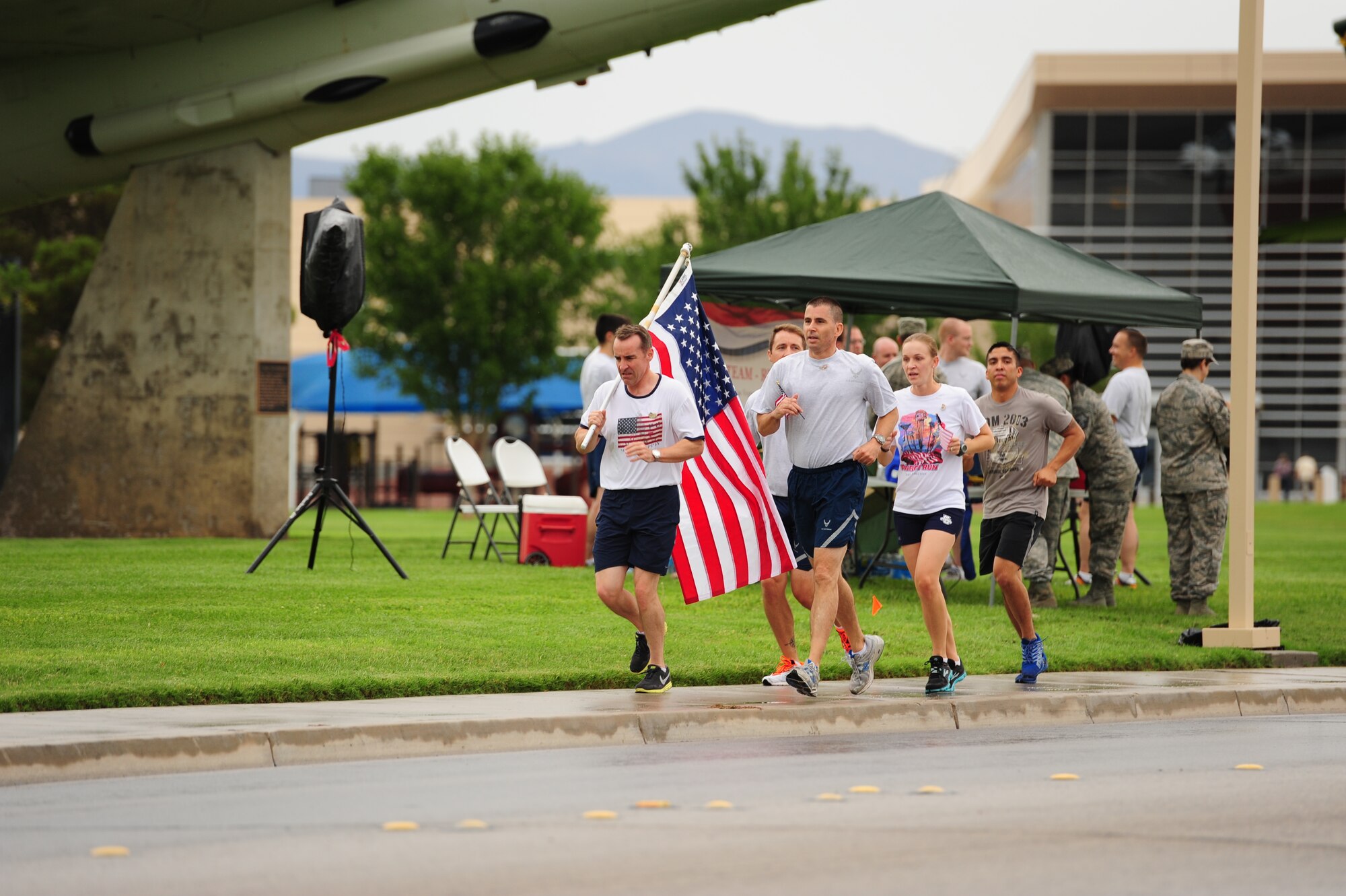 Col. Robert Ramsden (left), 99th Air Base Wing vice commander, and Chief Master Sgt. Steven Cleveland (right), 99th ABW command chief, and member from the 99th ABW command section participate in the 9/11 Old Glory Challenge Sept. 11, 2013, at Nellis Air Force Base, Nev. Squadrons from Nellis AFB took turns running with the flag around Freedom Park in tribute to those who lost their lives Sept. 11. The event was sponsored by the Top III and Team Red White and Blue Las Vegas. (U.S. Air Force photo by Staff Sgt. Michael Charles)