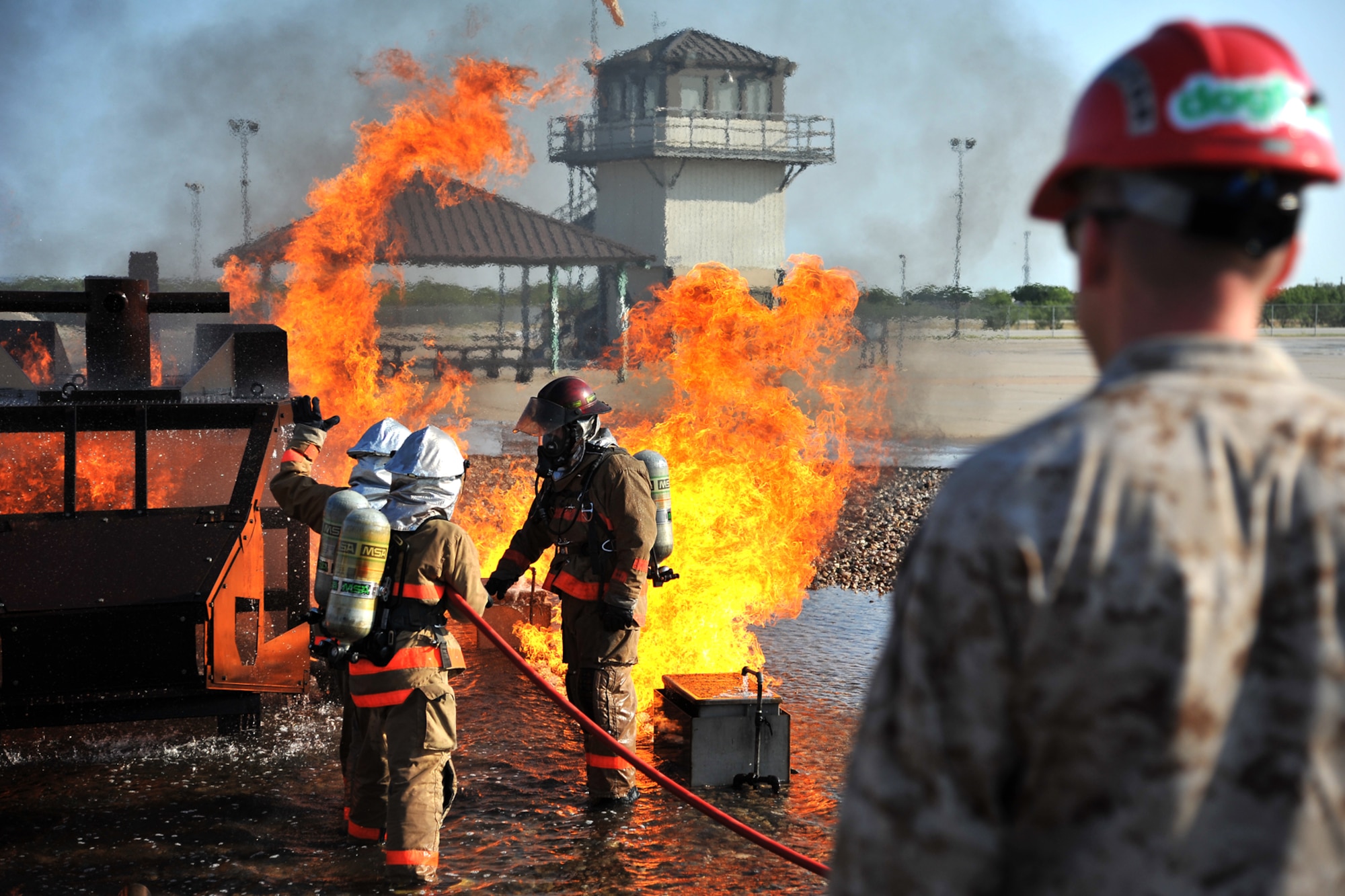 GOODFELLOW AIR FORCE BASE, Texas - An instructor from the 312th Training Squadron supervises as students put out a fire in the Helo Trainer at the Louis F. Garland Department of Defense Fire Academy Sept. 6. Students use the trainer in the sixth training block to help prepare them to face small aircraft fires in a real-life situation. (U.S. Air Force/ Senior Airman Michael Smith)