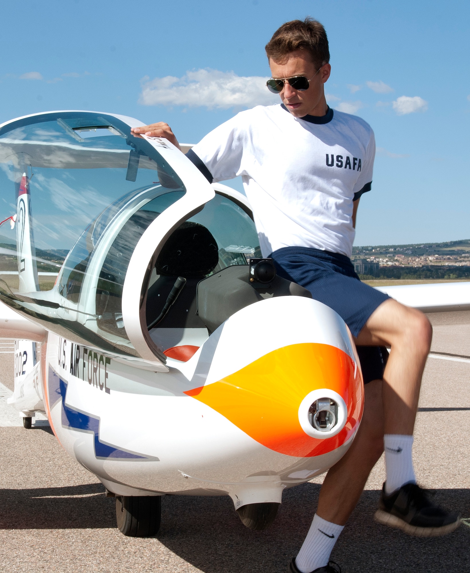 Cadet 3rd Class Adam Marcinkowski climbs into the cockpit of a TG-16A glider for his first solo flight at the Air Force Academy Airfield Sept. 17, 2013. Orange strips added to the front and sides of the glider are designed to enhance its visibility in the crowded airspace over the Academy. Marcinkowski is assigned to Cadet Squadron 30. (U.S. Air Force photo/Don Branum)