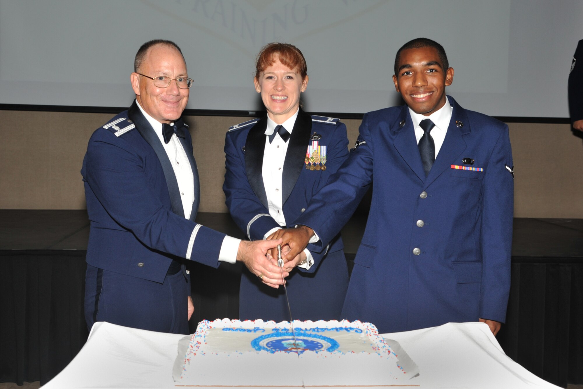 SAN ANGELO, Texas-- Chaplain (Lt. Col.) Steven Nicolai, 17th Training Wing, cuts the Air Force birthday cake with Airman Darrin Davis, 17th Contracting Squadron, and Col. Kimberlee Joos, 17th Training Wing commander, during the Goodfellow Air Force Base annual Air Force Ball Sept. 13 at the McNease Convention Center. Tradition dictates the oldest and youngest Air Force members at the base join together to cut the cake. (U.S. Air Force photo/Senior Airman Michael Smith)