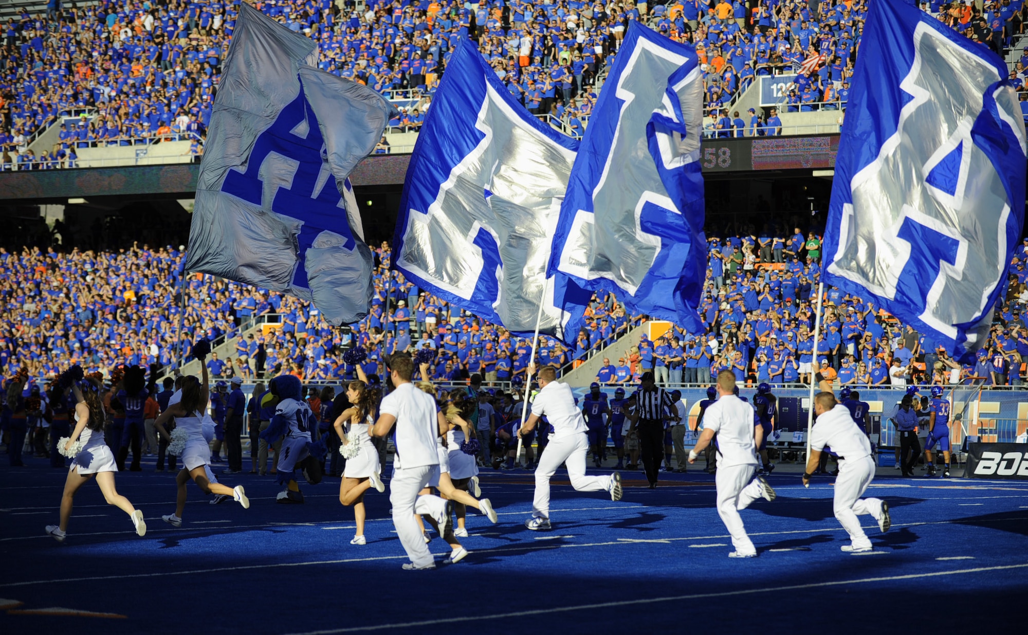 The Air Force Academy cheerleaders storm onto the field with flags held high Sept. 13, 2013, inside Bronco Stadium in Boise, Idaho. Air Force has scored a rushing touchdown in 50 straight games, dating back to the 2009 season. That is the longest active streak in the Football Bowl Subdivision. (U.S. Air Force photo by Senior Airman Benjamin Sutton/Released) 