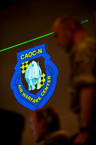 A Combined Air and Spaced Operations Center-Nellis patch is illuminated in the background during Coalition Virtual Flag Sept. 13, 2013, at Nellis Air Force Base, Nev. The CAOC-N hosts a number of virtual airspace exercises to include Virtual Flag. (U.S. Air Force photo/Senior Airman Brett Clashman)