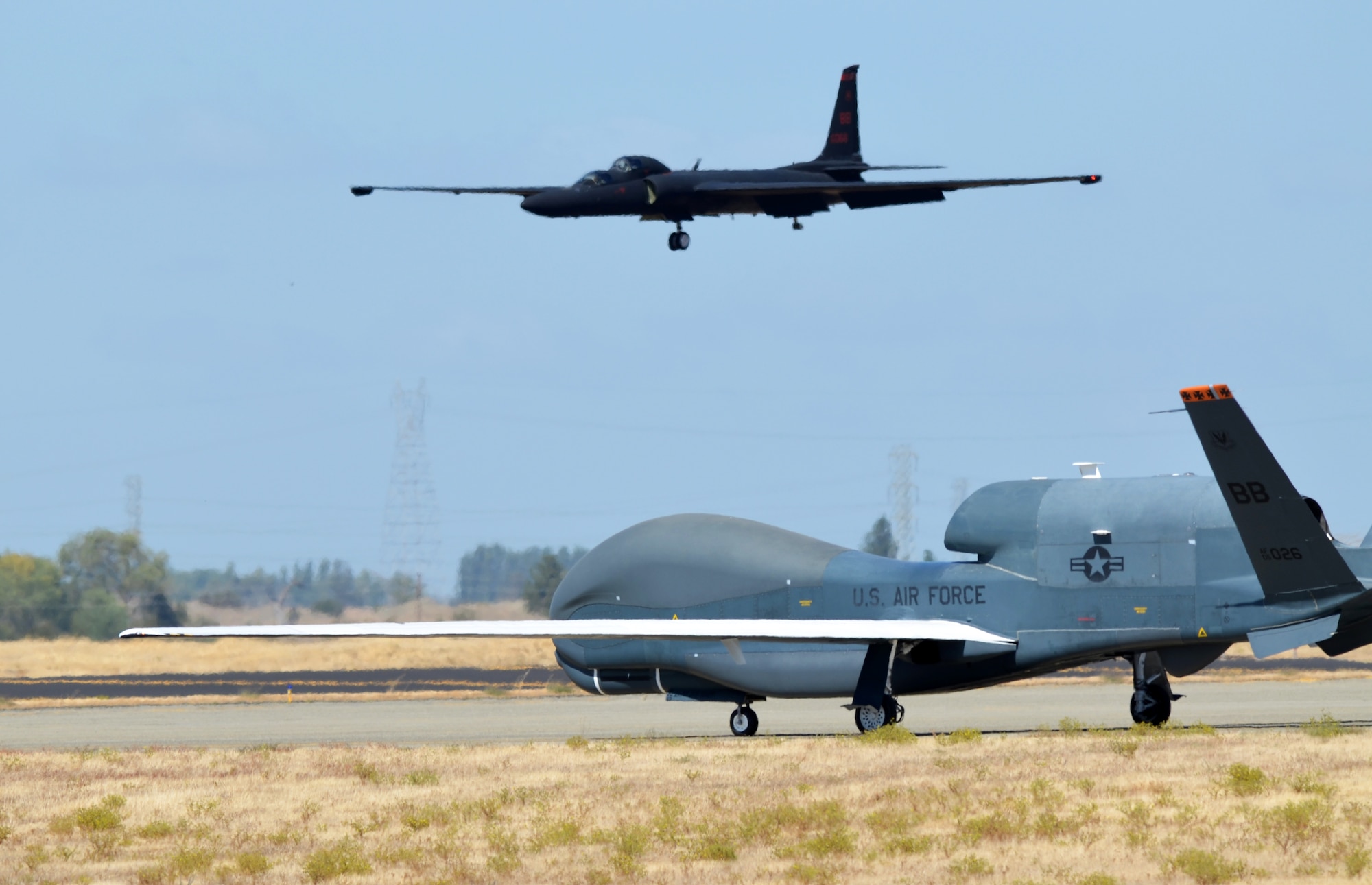 A RQ-4 Global Hawk taxies on the flightline as a U-2 Dragon Lady makes its final approach Sept. 17, 2013, at Beale Air Force Base, Calif. The RQ-4 and U-2 are the Air Force’s primary high-altitude intelligence, surveillance and reconnaissance aircraft. (U.S. Air Force photo by Airman 1st Class Bobby Cummings/Released)
