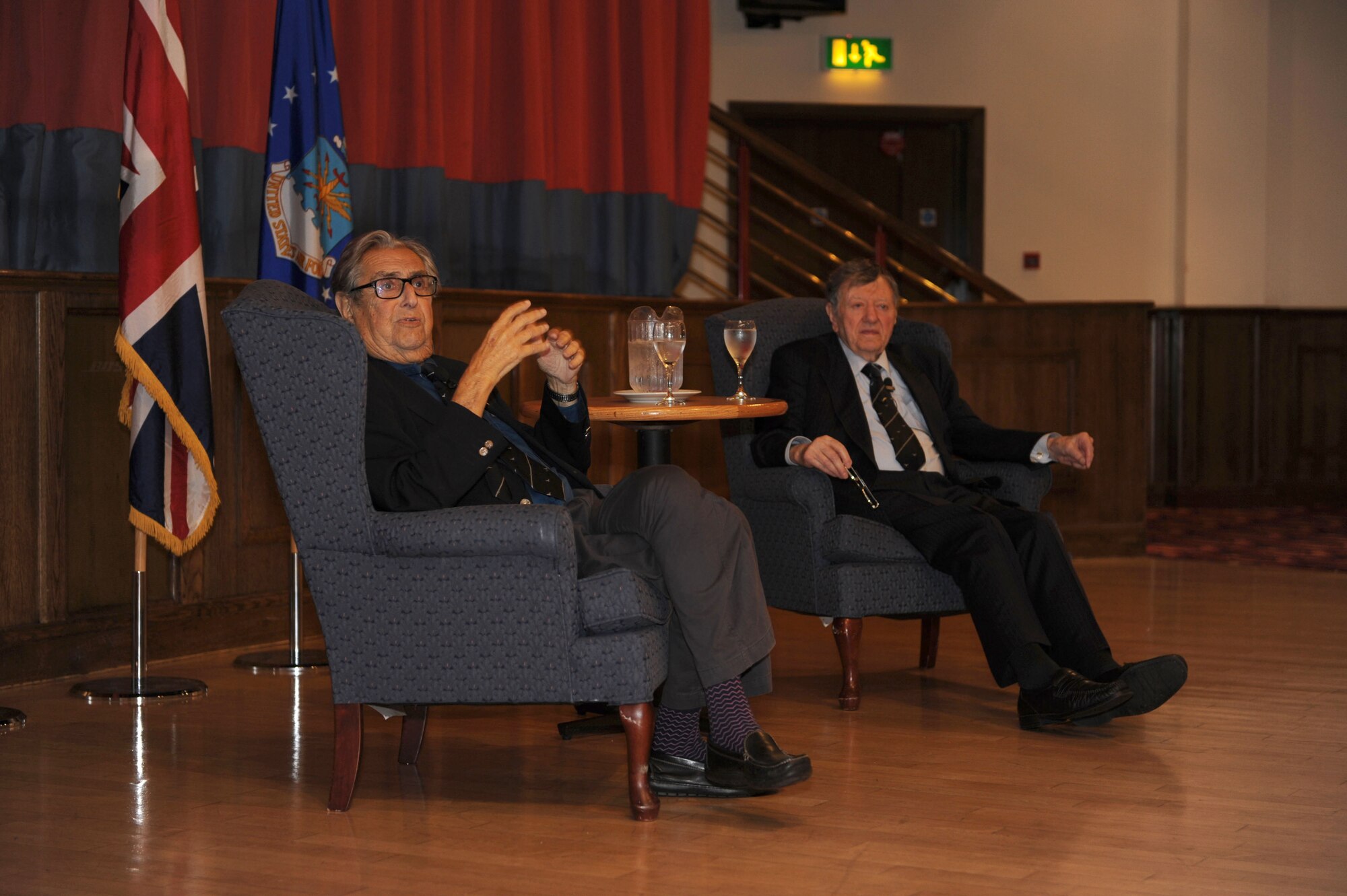 Andrew Wiseman, left, and retired Royal Air Force Cdre. Charles Clarke, both prisoners of war during World War II, tell stories during the Prisoner-Of-War/Missing-In-Action Remembrance Luncheon Sept. 18, 2013, in the Galaxy Club on RAF Mildenhall, England. Clarke and Wiseman were both held in Stalag Luft III, the POW camp portrayed in the film “The Great Escape.” (U.S. Air Force photo by Airman 1st Class Preston Webb/Released)