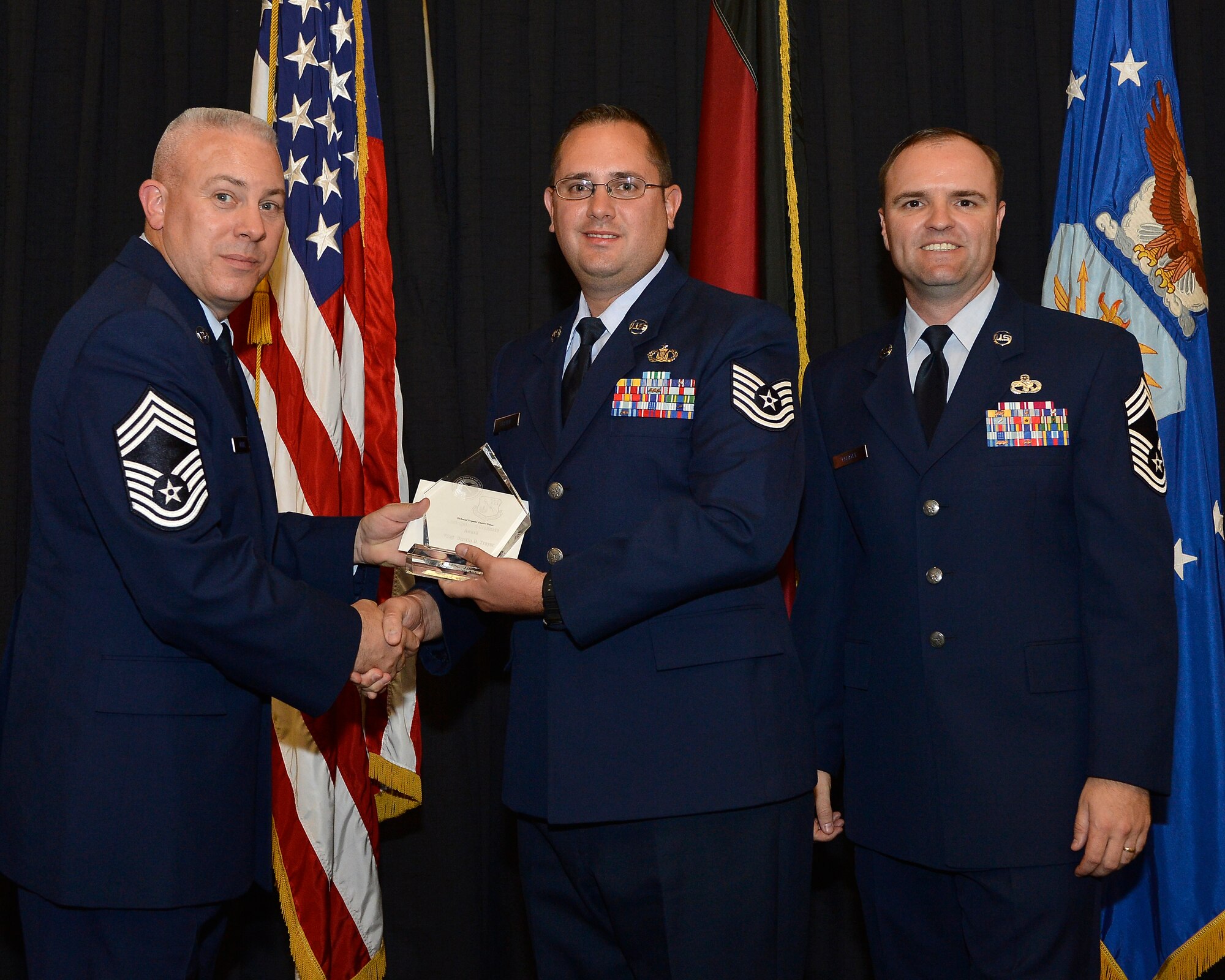 Tech. Sgt. Dustin Troyer, 39th Operations Squadron deputy airfield manager accepts a Kisling Noncommissioned Officer Academy Class 13-6 distinguished graduate award from Chief Master Sgt. Christopher Moore, Kisling NCOA commandant and Chief Master Sergeant Paul Elliott III, 86th Logistics Readiness Group superintendant. Troyer received the award during his graduation ceremony Sept. 5, 2013, at Ramstein Air Base, Germany. (U.S. Air Force photo by Airman 1st Class Jordan Castelan/Released)