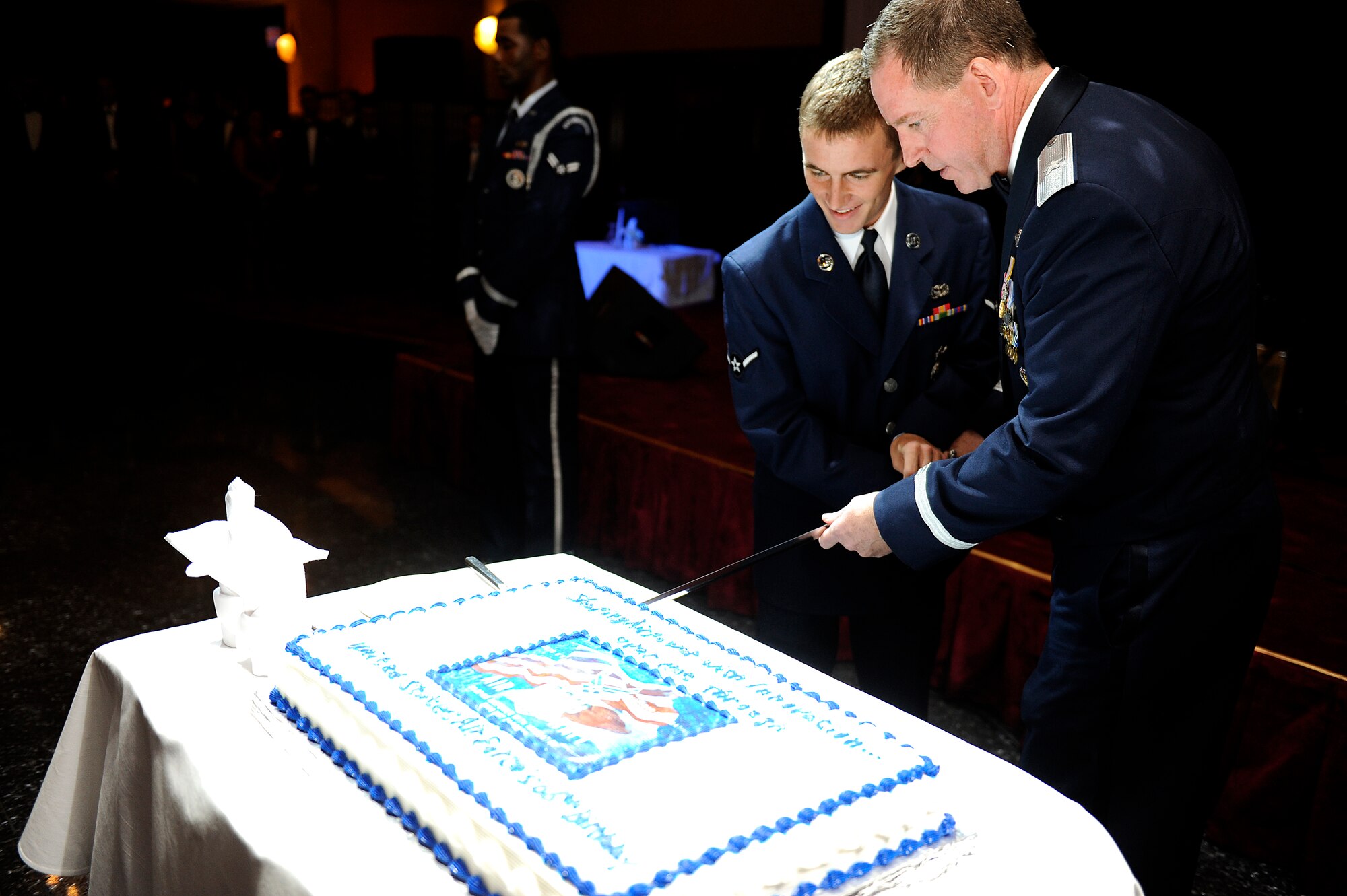 U.S. Air Force Brig. Gen. James Hecker, 18th Wing commander, and Airman Joshua Innis, 18th Security Forces Squadron installation entry controller, cut a cake with a saber during the 2013 Air Force Ball on Kadena Air Base, Japan, Sept. 14, 2013. As with tradition, a slice of cake is given to the most senior ranking and junior ranking Airmen to signify respect and honor afforded to experience and seniority while symbolizing how our experienced Airmen have nurtured and led young Airmen to fill the ranks. (U.S. Air Force photo by Senior Airman Maeson L. Elleman)