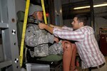 Chris Fleczak, manager of the Army's Occupant Protection Lab, adjusts a test dummy in one of the lab's impact simulators at Selfridge Air National Guard Base, Aug. 29, 2013.