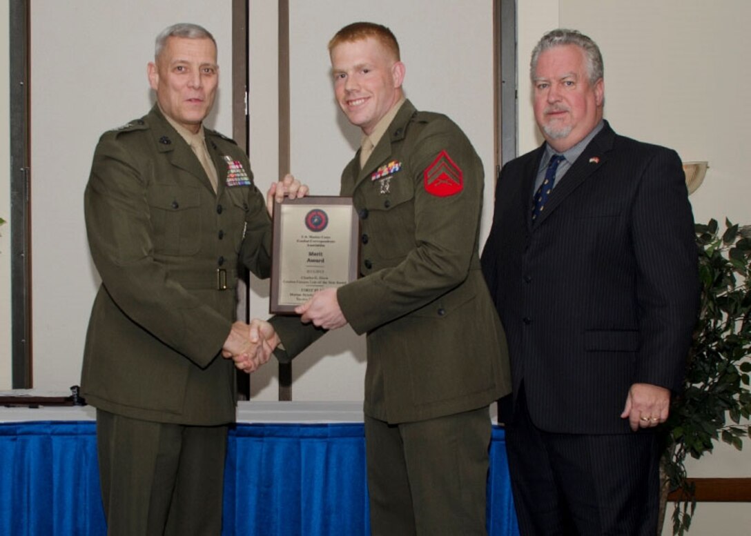 U.S. Marine Cpl. Bryan Nygaard, (center), Marketing and Public Affairs representative for Recruiting Station Baltimore, receives the Merit Award for best Personality Feature from Assistant Commandant of the Marine Corps Lt. Gen. John Paxton, left, and President of the United States Marine Corps Combat Correspondent Association Bill Hauptfleisch at Joint Base Andrews, July 27, 2013.  The awards are given annually by the USMCCCA to service members who display excellence in journalism. Nygaard, a native of Ocala, Fla., won the award for an article titled “Illinois Corpsman works with Combat Engineers, proves his worth in Garmsir” which he wrote while deployed with II Marine Expeditionary Force in Afghanistan. (U.S. Marine Corps photo by Staff Sgt. Jeffrey Anderson/Released)