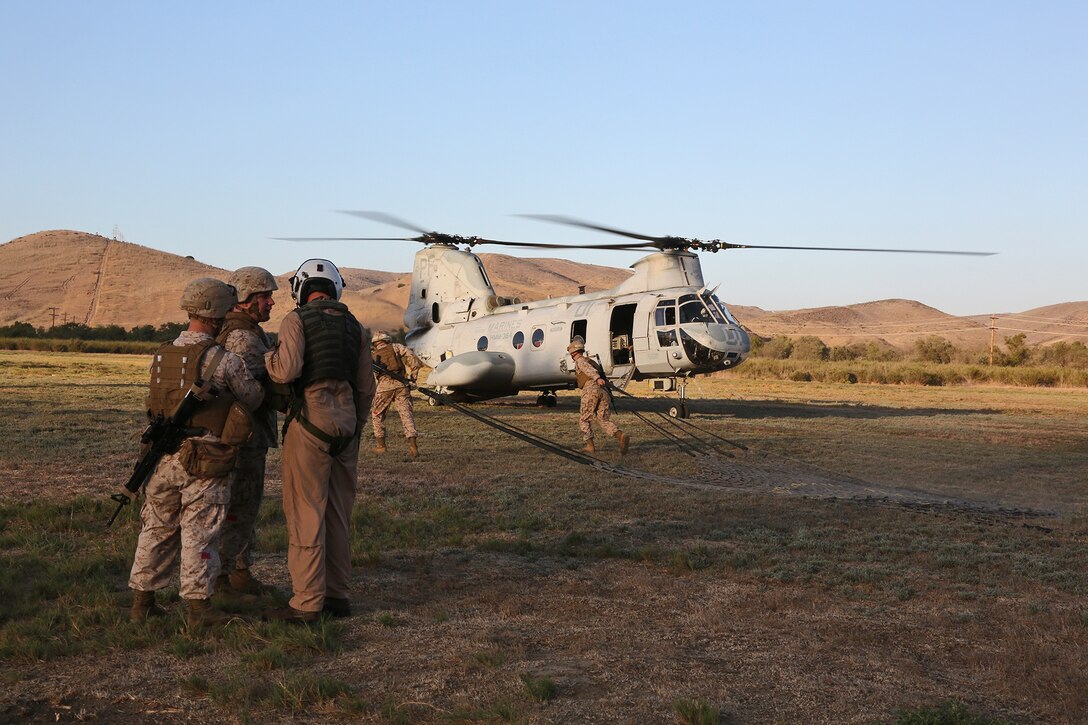 Marines with Landing Support Company, Combat Logistics Regiment 17, 1st Marine Logistics Group, discuss plans with a pilot from Marine Medium Helicopter Squadron 364, during a helicopter support team training operation aboard Camp Pendleton, Calif., Sept. 17, 2013. The seven-man HST was responsible for the safe and timely external lift of cargo under two CH-46 Sea Knights. 