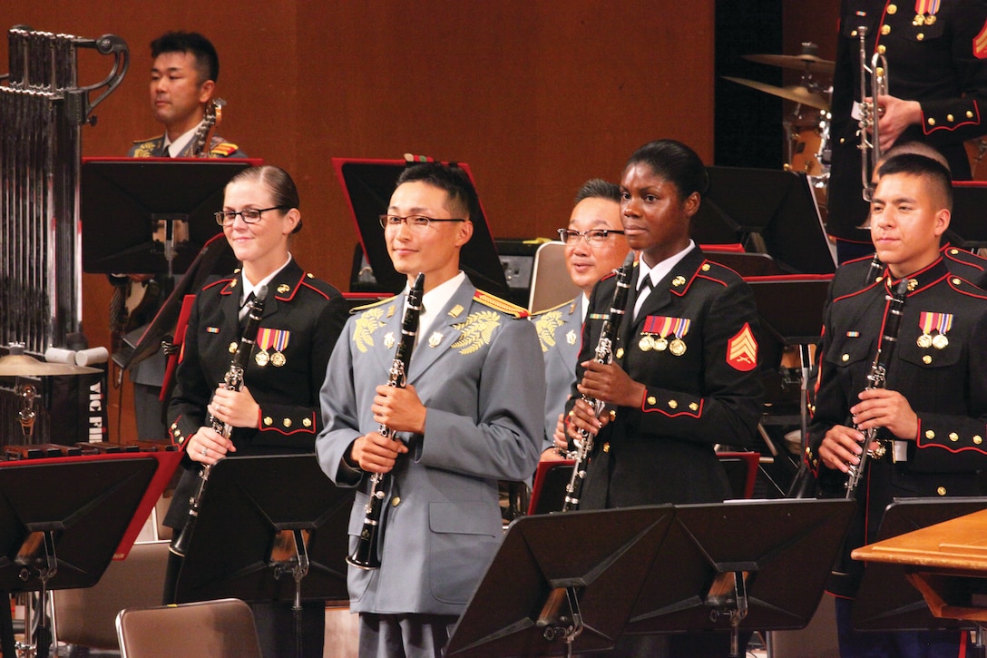 Musicians with the Japan Ground Self-Defense Force 15th Band and the III Marine Expeditionary Force Band stand during applause from a full-capacity crowd Sept. 14 at the Okinawa Civic Hall in Okinawa City during the 18th Annual Combined Band Concert. The bands intend to continue their tradition of hosting combined concerts.