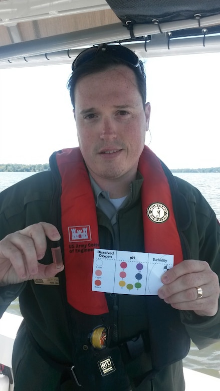 Trey Church, natural resource specialist at Old Hickory Lake, holds up the dissolved oxygen to the dissolved oxygen color chart for recording the results collected at river mile 237 on the Cumberland River for the 2013 World Water Monitoring Challenge™ Sept. 13, 2013. 