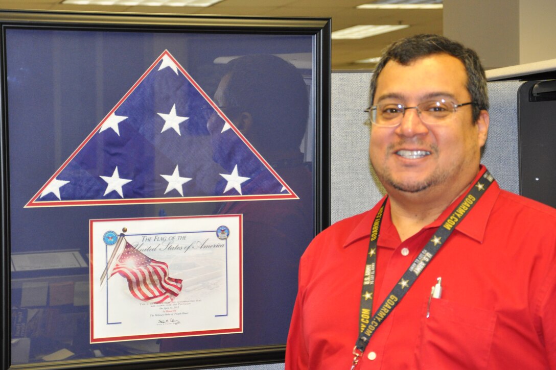 Luis Rivera-Rios stands by a flag that was flown over the Pentagon in recognition of the 25th Anniversary of the Military Order of the Purple Heart.