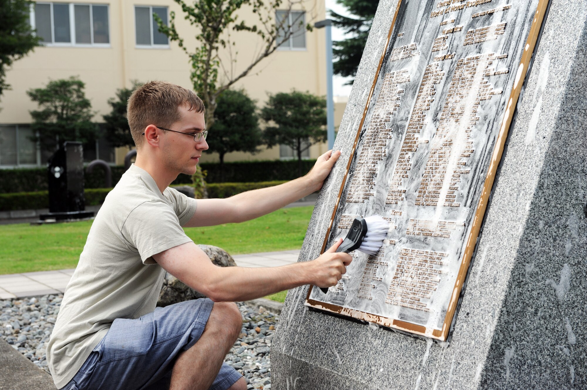 Airman 1st Class Luke MacFarlane, 374th Communications Squadron, scrubs the Medal of Honor Recipients monument in front of the 374th Airlift Wing headquarters at Yokota Air Base, Japan, Sept. 14, 2013. The monument lists U.S. Air Force recipients from World War I, World War II, the Korea War and the Vietnam War. (U.S. Air Force photo by Senior Airman Desiree Economides/Released)