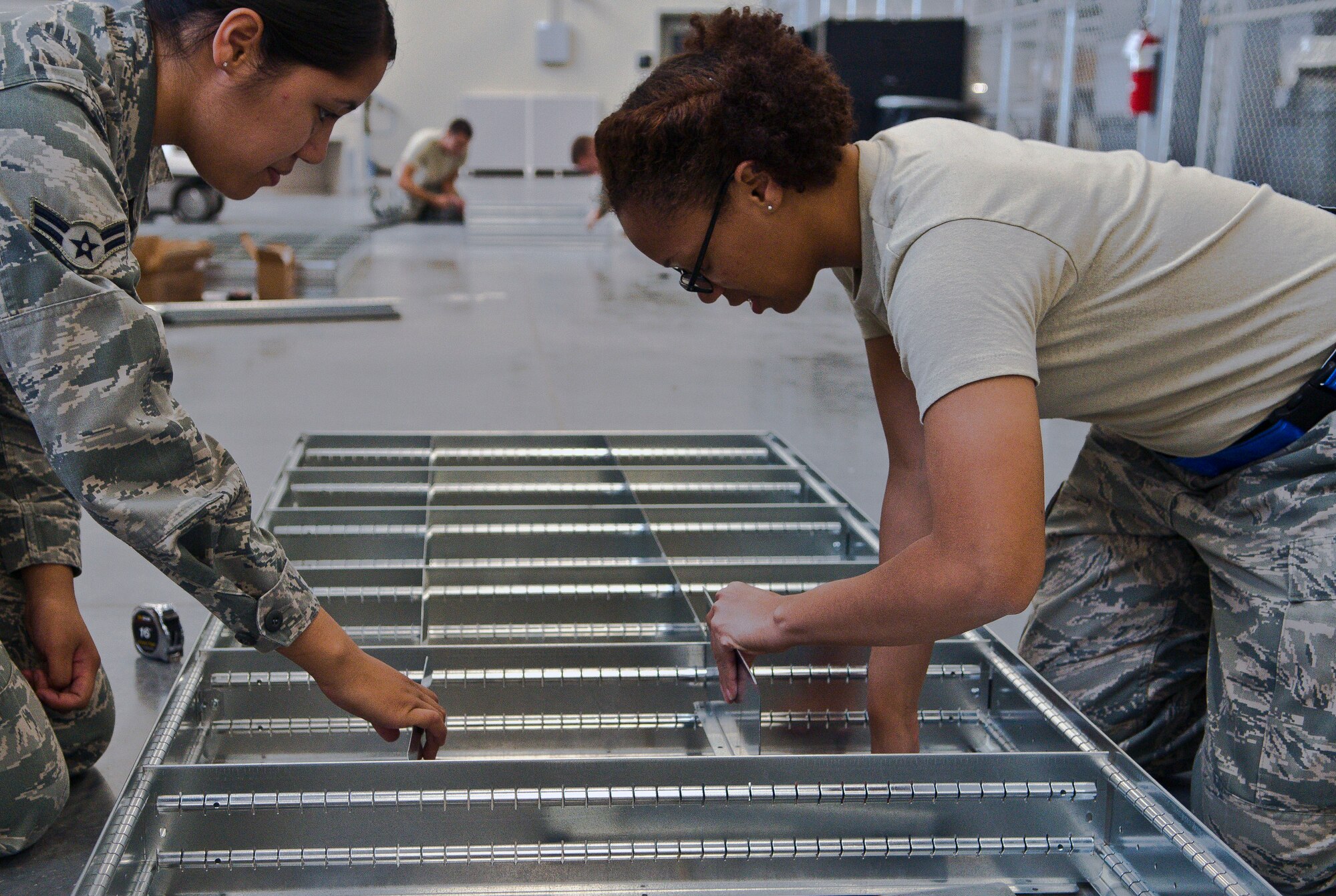 U.S. Air Force Airman 1st Class Charleesiama Green (right), a 366th Logistics Readiness Squadron material management apprentice from Baltimore, assembles dividers on an automated, rotating bench-stock supply cabinet at Mountain Home Air Force Base, Idaho, Sept. 19, 2013. Airman 1st Class Delsa Saseve, from Reno, Nev., assists her with the task. Green and her teammates are working overtime to complete a state-of-the-art consolidated supply warehouse, scheduled to be complete in late December 2013. Green takes pride in knowing at the end of a 10- to 12-hour shift, she’s accomplished something bigger than her, something that will impact the entire 366th Fighter Wing, she said. (U.S. Air Force photo by Master Sgt. Kevin Wallace/RELEASED)