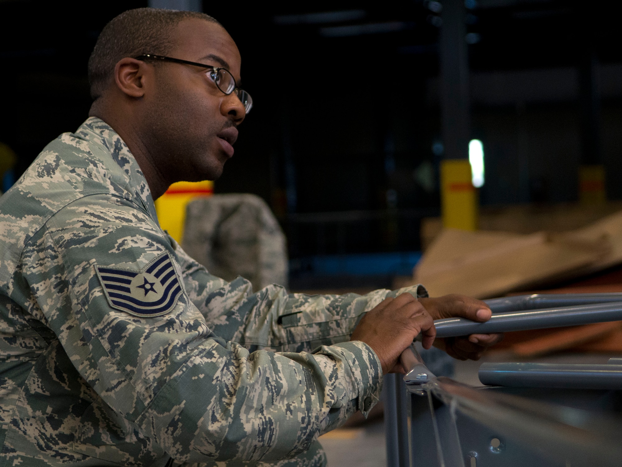 U.S. Air Force Tech. Sgt. Harold Andrews, a 366th Logistics Readiness Squadron material management craftsman from Idabel, Okla., stabilizes a ladder brace as three of his subordinate Airmen bolt down and secure the braces. As a 366th LRS NCO, Andrews oversees and assists in tasks, while ensuring safety, good order, and discipline are maintained, as his flight works two to three hours after normal duty shifts to complete a state-of-the-art consolidated supply warehouse, which will house hundreds of millions of dollars in F-15E Strike Eagle parts and components. Though his Airmen remain motivated during their extended shifts, NCOs are vital in keeping the team focused and safe. (U.S. Air Force photo by Master Sgt. Kevin Wallace/RELEASED)