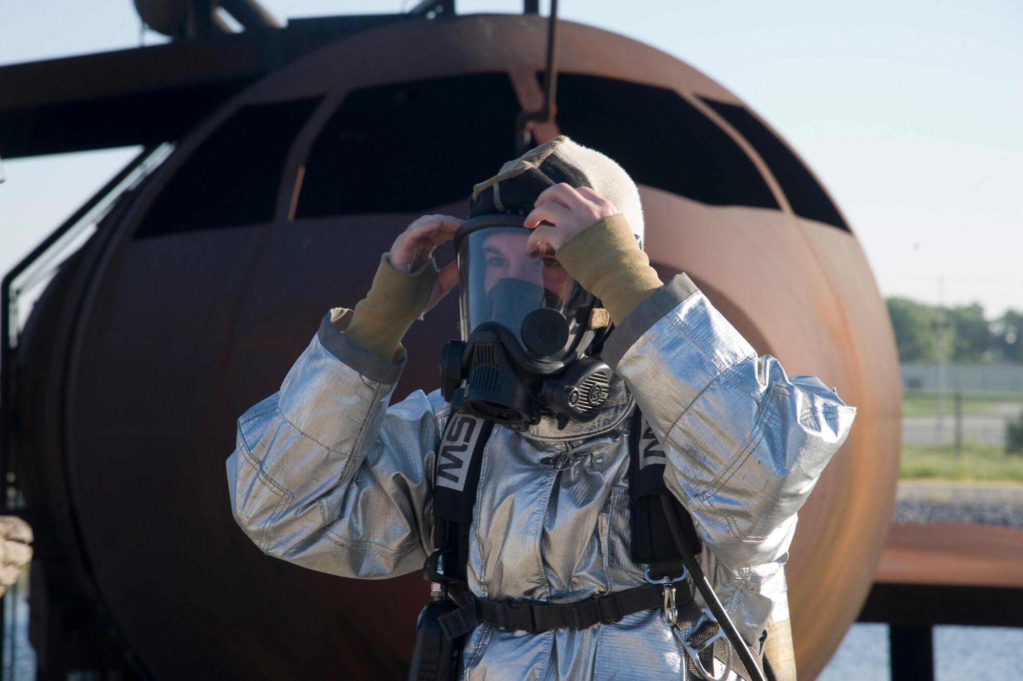 Airman 1st Class Erich Laranaga, 22nd Civil Engineering firefighter, dawns a fire protection mask during a live-fire training exercise Aug. 27, 2013, at McConnell Air Force Base, Kan. His gear is coated with a silver lining to reflect the heat from metal and fuel fires. (U.S. Air Force photo/Airman 1st Class John Linzmeier)