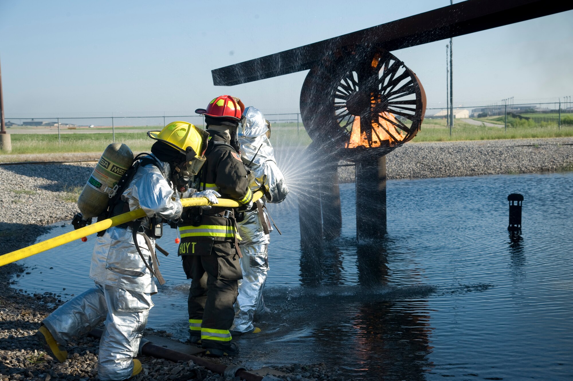 Firefighters approach a trainer aircraft with a fire attack hose Aug. 27, 2013, at McConnell Air Force Base, Kan. The hose nozzle is capable of dispersing water in different patterns to extinguish fires effectively. (U.S. Air Force photo/Airman 1st Class John Linzmeier)