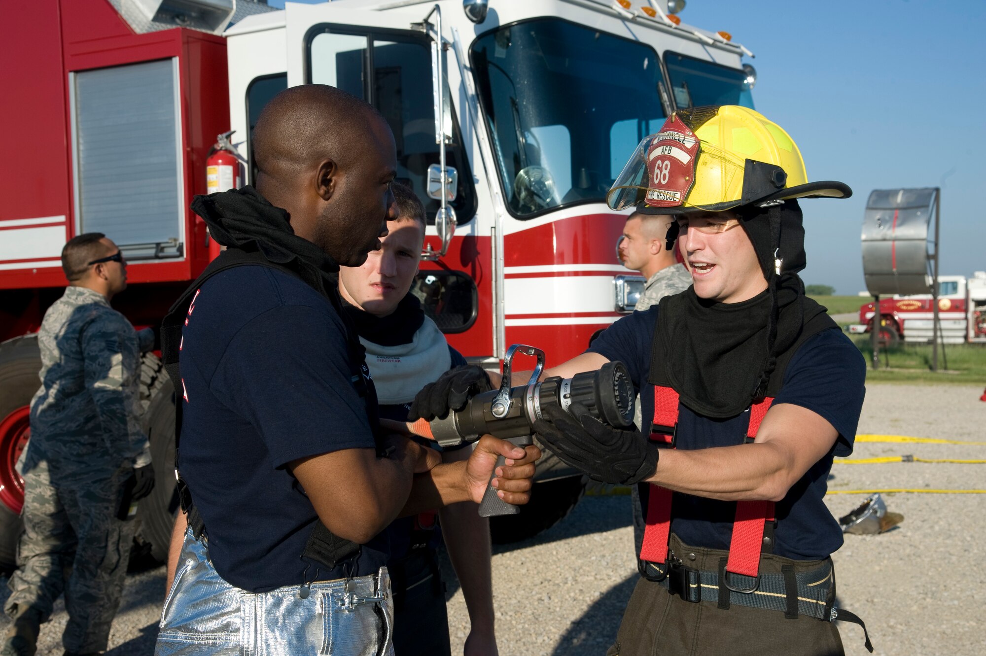 Senior Airman, Eloy F. Garcia, 22nd Civil Engineering Squadron firefighter and driver operator, shows Senior Master Sgt. Clark how to properly use a fire attack hose during a live fire training exercise Aug. 27, 2013, at McConnell Air Force Base, Kan. At least two firefighters are needed to safely operate the attack line. (U.S. Air Force photo/Airman 1st Class John Linzmeier)