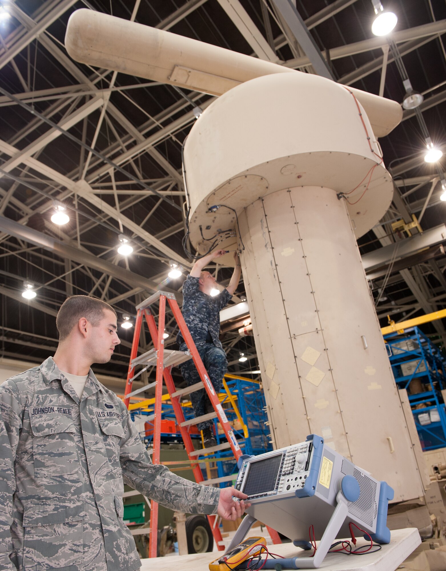 Airman 1st Class James Johnson-Reale, 87th Communications Squadron radar technician, enters settings into a spectrum analyzer while Petty Officer 2nd Class Matthew Feldt, 87th CS electronics technician, connects test cables to a MPN-25 Airport Approach Radar Sept. 12, 2013, at Joint Base McGuire-Dix-Lakehurst, N.J. The squadron first deployed the radar to Afghanistan during Operation Enduring Freedom. (U.S. Air Force photo by Carlos Cintron/Released)