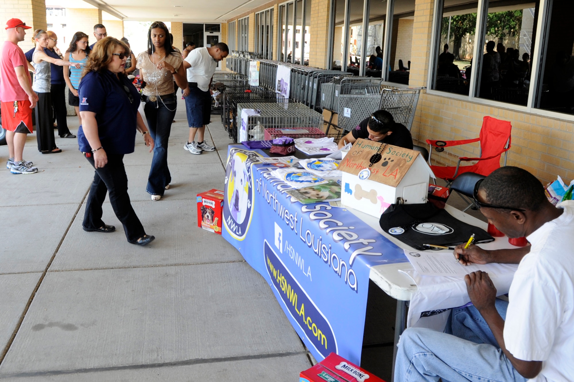 Prospective dog owners fill out adoption paperwork as others look for the perfect pet during the Humane Society of Northwest Louisiana adoption event at the Barksdale Exchange on Barksdale Air Force Base, La., Sept. 14, 2013. HSNWL reported that the event was one of their most successful, with 10 of the 15 animals brought to the event being adopted. (U.S. Air Force photo by Master Sgt. Jeff Walston/Released)