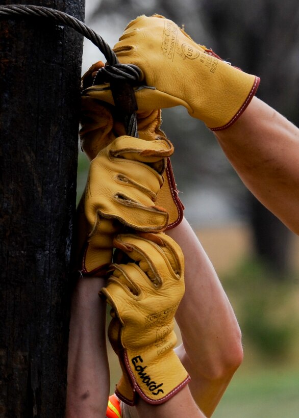 Airmen from the 28th Civil Engineer Squadron electrical systems shop tie a steel cable around a new utility pole during an equipment upgrade at Ellsworth Air Force Base, S.D., Sept. 13, 2013. The utility poles hold power lines that provide electricity to all base facilities. (U.S. Air Force photo by Airman 1st Class Anania Tekurio/Released)