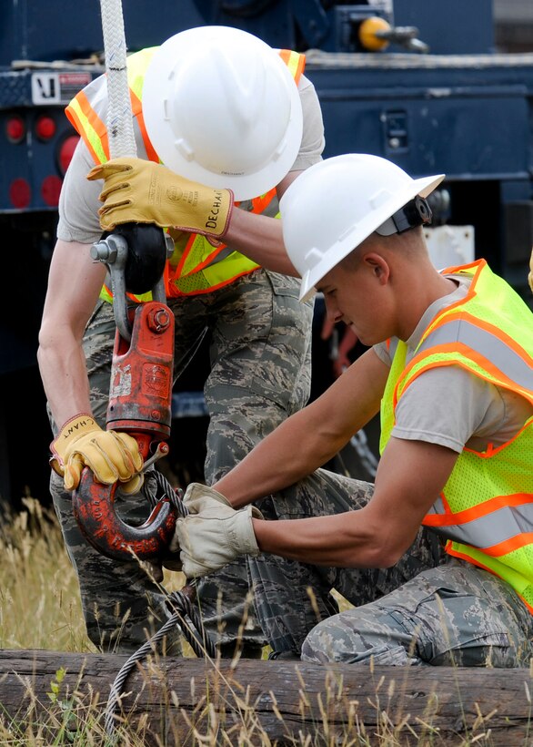 Airmen 1st Class Daniel Dechant (left) and Kaleb Johnson, 28th Civil Engineer Squadron electrical systems technicians, secure a cable to a new utility pole during an equipment upgrade at Ellsworth Air Force Base, S.D., Sept. 13, 2013. The technicians used heavy machinery and reinforced cables to secure the 30 - foot, 2,000-pound pole. (U.S. Air Force photo by Airman 1st Class Anania Tekurio/Released)