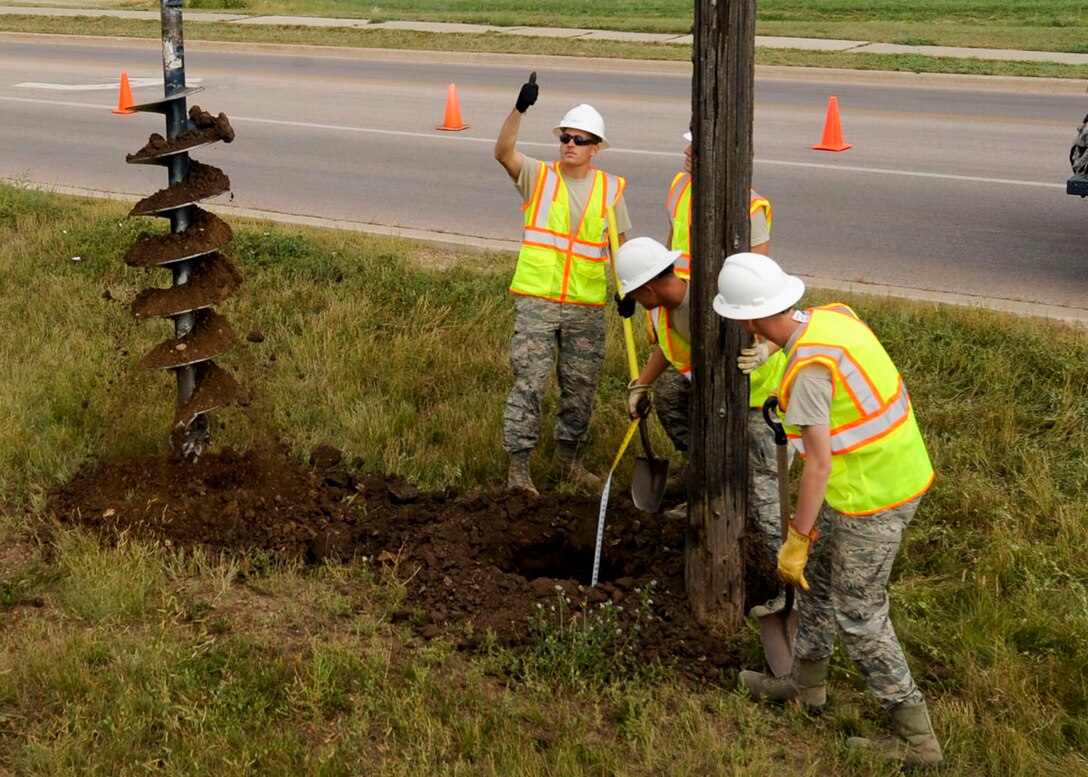 Senior Airman Josh Kohler, 28th Civil Engineer Squadron electrical systems technician, directs the auger operator during the replacement of an old utility pole at Ellsworth Air Force Base, S.D., Sept. 13, 2013. In addition to servicing equipment, Airmen from the 28th CES electrical systems shop install, modify and repair a wide variety of electrical equipment and systems basewide. (U.S. Air Force photo by Airman 1st Class Anania Tekurio/Released)