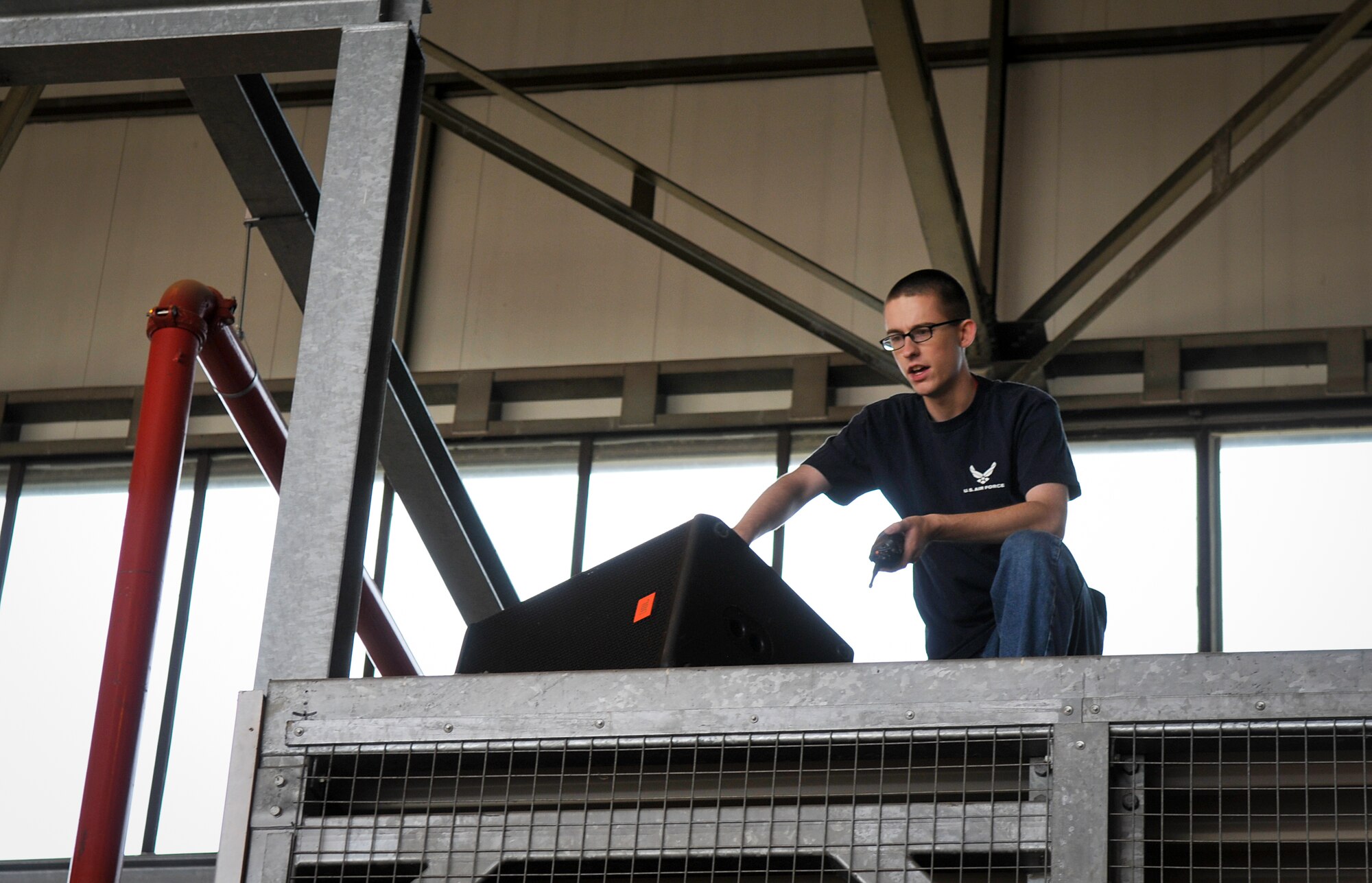 Airman 1st Class Joseph Leroy, 86th Communications Squadron radio frequency transmissions systems technician, gives direction while setting up the sound system in a hangar for the Ramstein Welfare Bazaar, Sept. 9, 2013, Ramstein Air Base, Germany. Leroy was part of a team of volunteers that helped set up and maintained the sound system during the bazaar. (U.S. Air Force photo/Senior Airman Jose L. Leon)