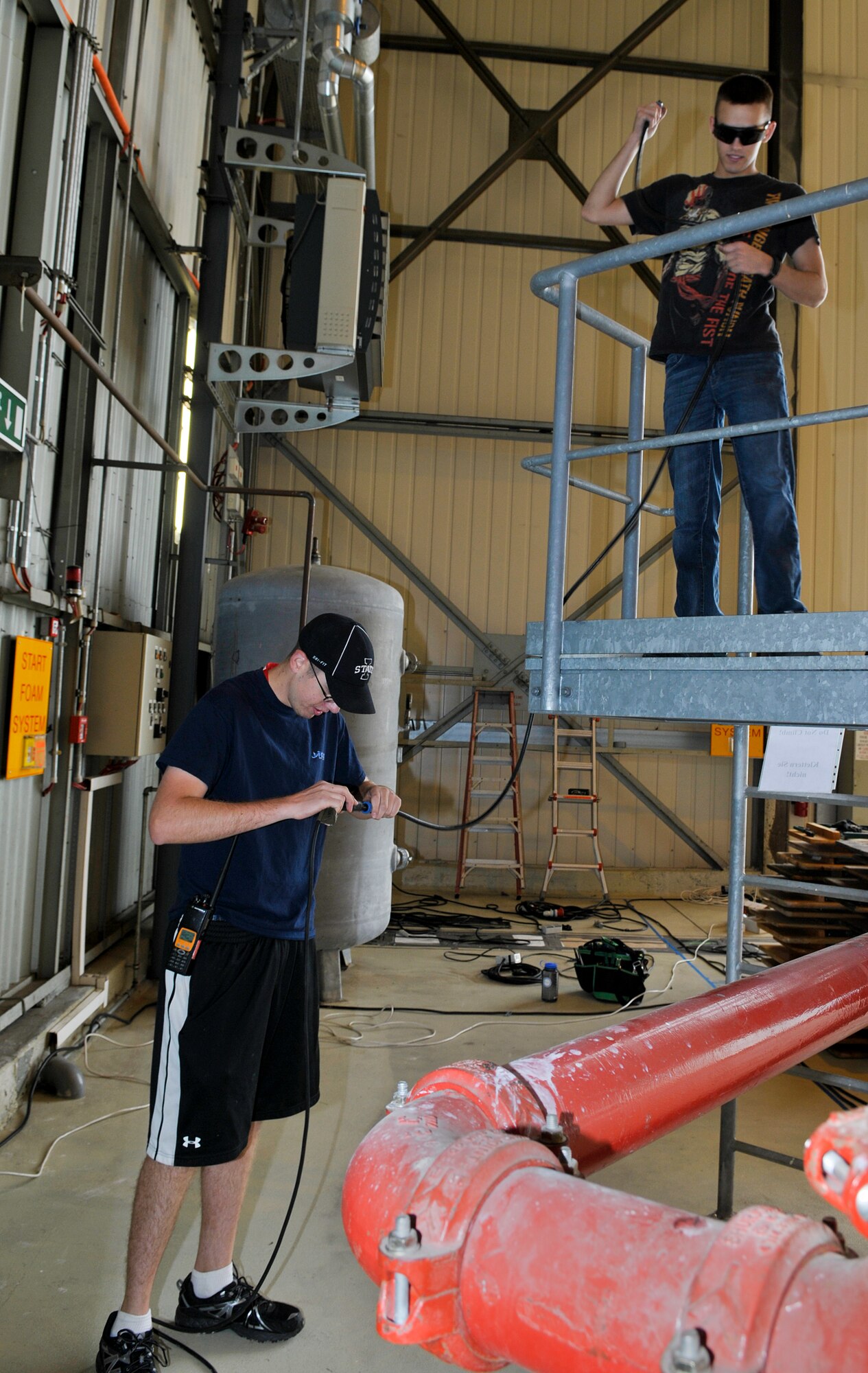 Senior Airman Andrew Miller and Airman 1st Class Brandon Daniel, 86th Communications Squadron radio frequency transmissions systems technicians, install speakers in a hangar for the Ramstein Welfare Bazaar, Sept. 9, 2013, Ramstein Air Base, Germany. Miller and Daniel were two of more than 300 volunteers assisting in the set-up for the bazaar. (U.S. Air Force photo/Senior Airman Jose L. Leon)