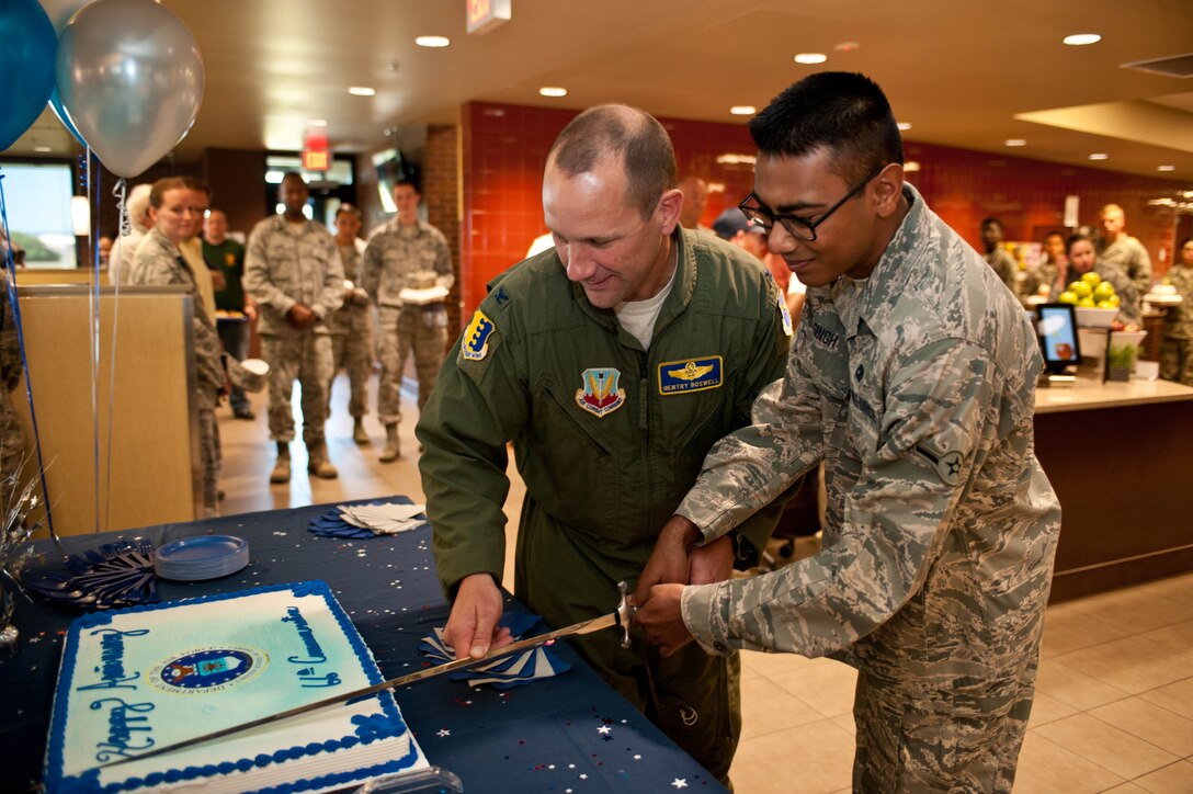 Col. Gentry Boswell, 28th Bomb Wing vice commander, and Airman Deonaraine Singh, 28th Aircraft Maintenance Squadron hydraulics technician, and the youngest Airman on base, cut a birthday cake during a celebration in honor of the Air Force’s 66th birthday in the Raider Café at Ellsworth Air Force Base, S.D., Sept. 18, 2013. The cake-cutting tradition has long since symbolized the passing down of wisdom from senior to junior servicemembers. (U.S. Air Force photo by Airman 1st Class Zachary Hada/Released)