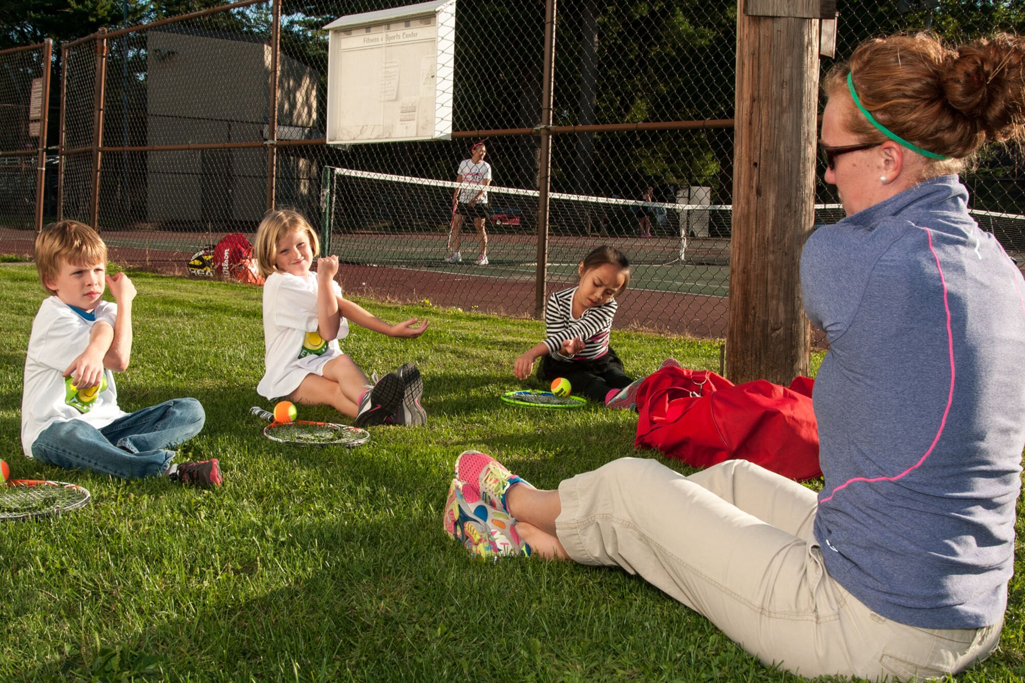 HANSCOM AIR FORCE BASE, Mass. -- During a Youth Center Smart Start tennis lesson Sept. 17, Ann-Marie Ely, Youth Sports and Fitness director, leads (left to right) Joseph Carey, Annalisa Wirthlin and Kohana Maguadog through stretching exercises prior to beginning tennis lessons. The Youth Center Smart Start tennis program teaches children ages three to eight the basics of the sport. (U.S. Air Force photo by Mark Herlihy)