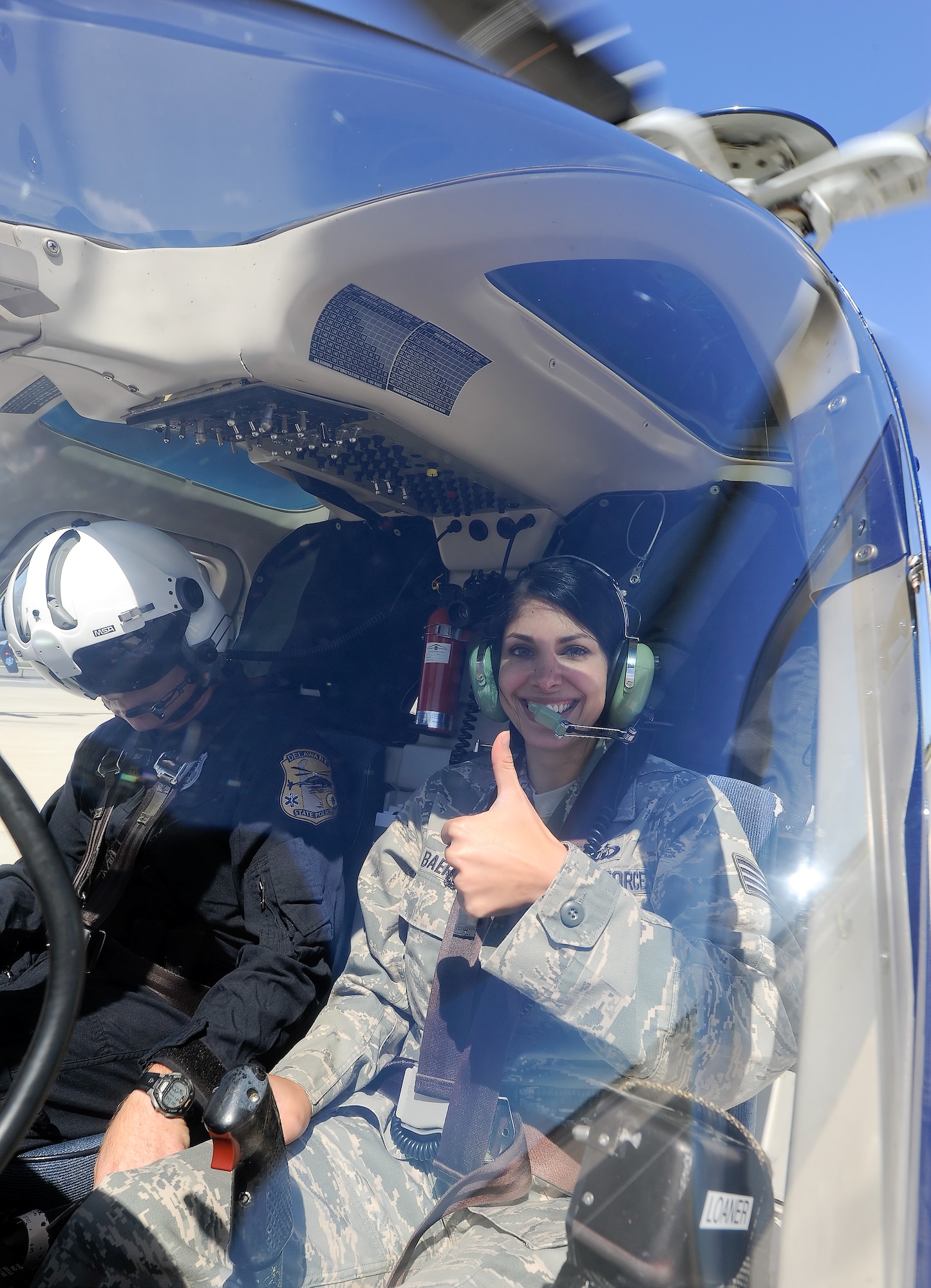 A broad smile and thumbs-up from the cockpit from Staff Sgt. Vanessa Baer of the 436th Operations Support Squadron, radar approach control section, indicating she is ready to go for a familiarization flight in a Delaware State Police Bell 407 helicopter on Sept. 18, 2013 at Dover Air Force Base, Del. RAPCON controllers, who primarily work with large transport jets at Dover gained insight in to the world of helicopter operations through a briefing and orientation flight with the Delaware State Police, aviation section. (U.S. Air Force photo/Greg L. Davis)