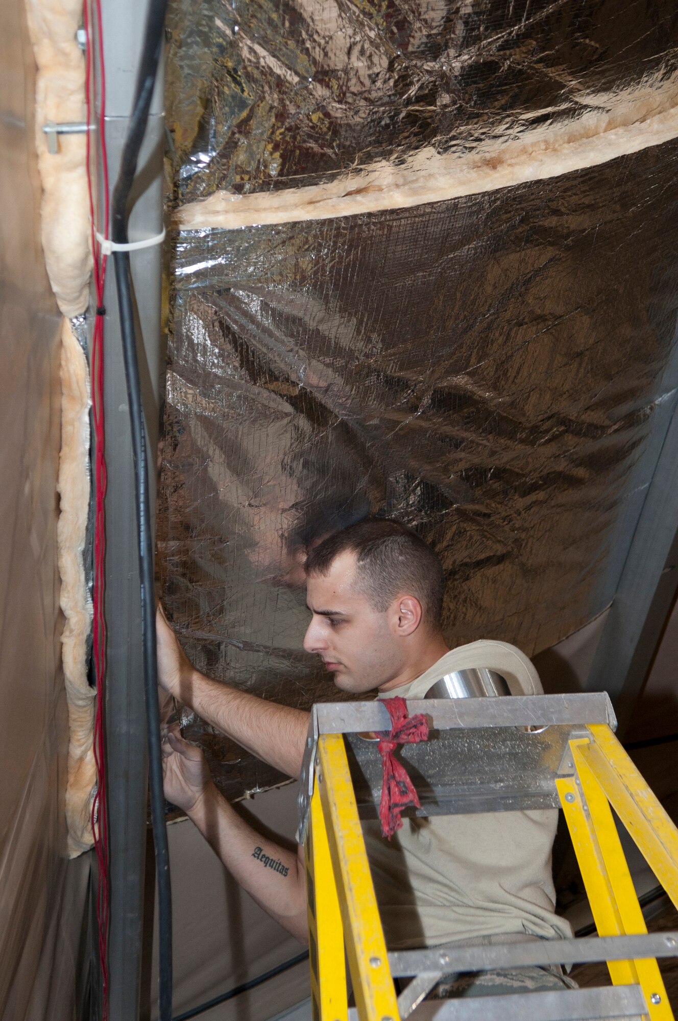 Senior Airman Dustyne Timm, 376th Expeditionary Civil Engineer Squadron structural journeyman, secures fiberglass insulation into the ceiling of the main fitness center at Transit Center at Manas, Kyrgyzstan, Sept. 16, 2013. Timm is deployed out of Altus Air Force Base, Okla., and is a native of Allenton, Wis. (U.S. Air Force photo/Staff Sgt. Robert Barnett)