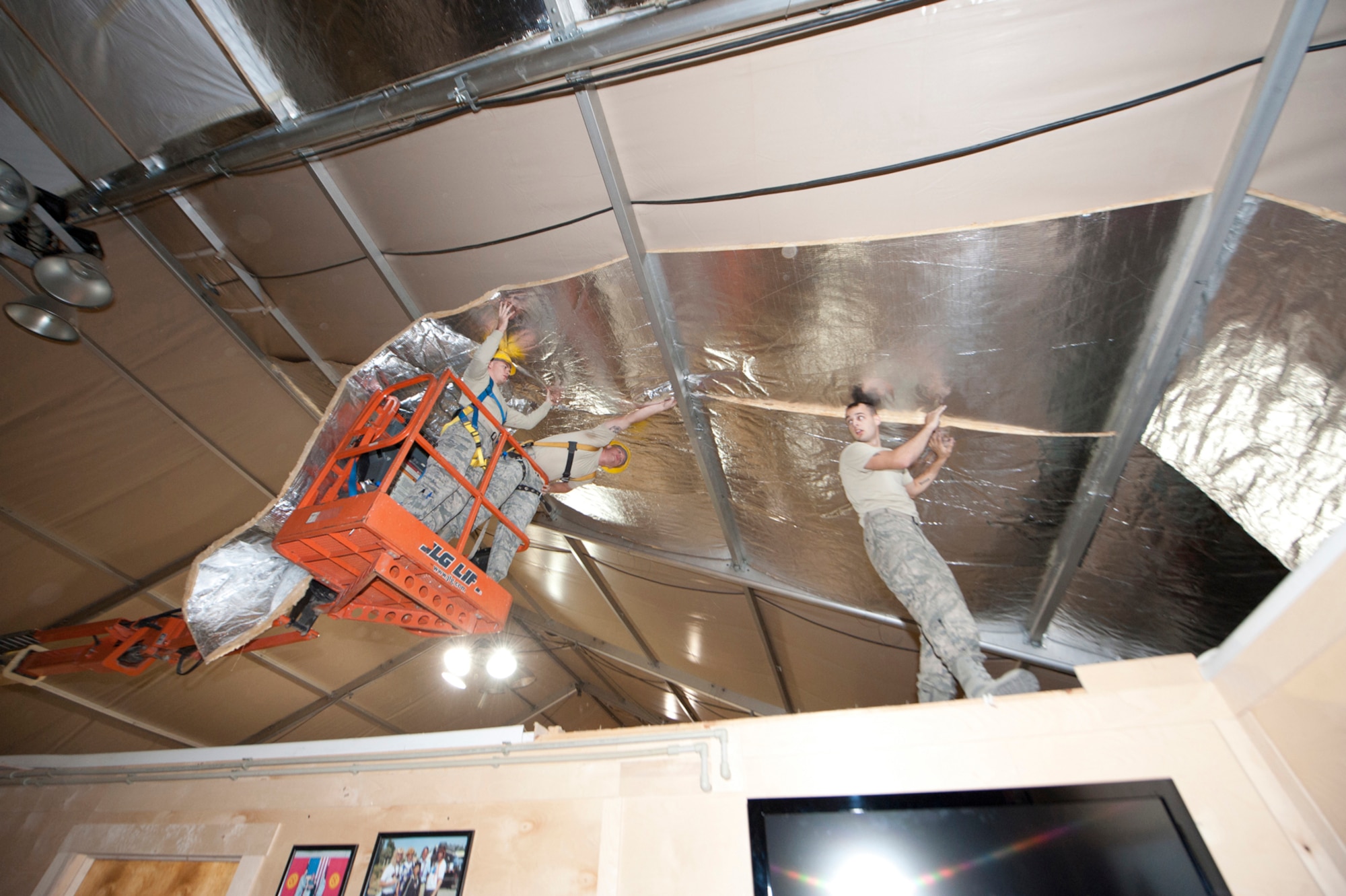 Members of the 376th Expeditionary Civil Engineer Squadron install insulation into the ceiling of the main fitness center to keep it warm during the winter at Transit Center at Manas, Kyrgyzstan, Sept. 16, 2013. Last year, the gym was cold enough for service members to see their breath. (U.S. Air Force photo/Staff Sgt. Robert Barnett)