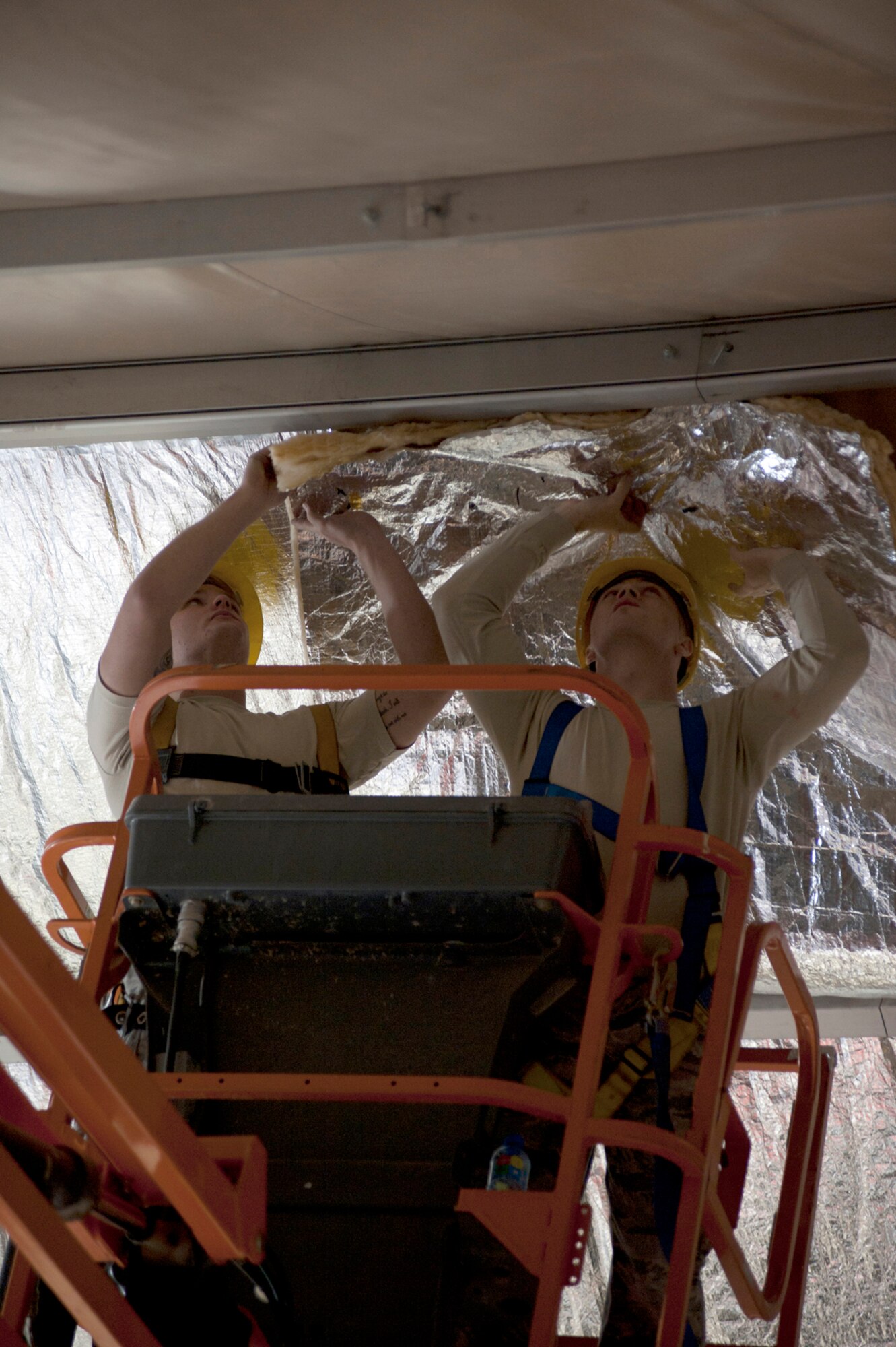 Airman 1st Class Larry Finch, left, and Airman 1st Class Chad Chapman, 376th Expeditionary Civil Engineer Squadron structural engineers, place insulation into the ceiling of the main fitness center at Transit Center at Manas, Kyrgyzstan, Sept. 16, 2013. Chapman is deployed out of Altus Air Force Base, Okla., and is a native of Shelton, Wash. Finch is also deployed out of Altus Air Force Base, Okla., and is a native of Aztec, N.M. (U.S. Air Force photo/Staff Sgt. Robert Barnett)