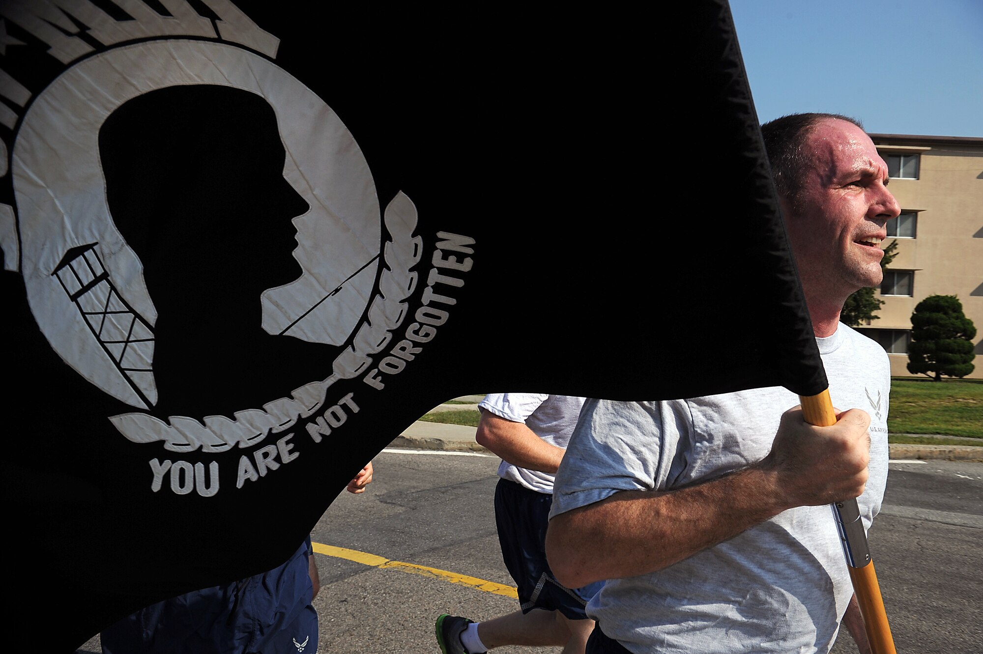 Airmen from the 51st Maintenance Operations Flight run in formation with the official Prisoner of War/Missing in Action flag as part of a 24-hour run during POW/MIA week at Osan Air Base, Republic of Korea, Sept. 18, 2013. An act of Congress established this day by the passage of Section 1082 of the 1998 Defense Authorization Act, and it is one of only six days a year the POW/MIA Flag can be flown. (U.S. Air Force photo/Staff Sgt. Sara Csurilla)
