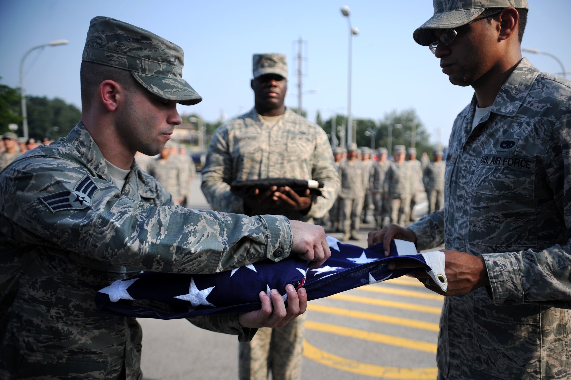Two Osan Honor Guardsmen fold the American flag as another carries the Prisoner of War/Missing in Action flag during a retreat ceremony to honor POW/MIA week at Osan Air Base, Republic of Korea, Sept. 18, 2013. National POW/MIA Recognition Day is a day reserved to remember, reflect on and honor the sacrifices made by the nation's heroes. (U.S. Air Force photo/Staff Sgt. Sara Csurilla)