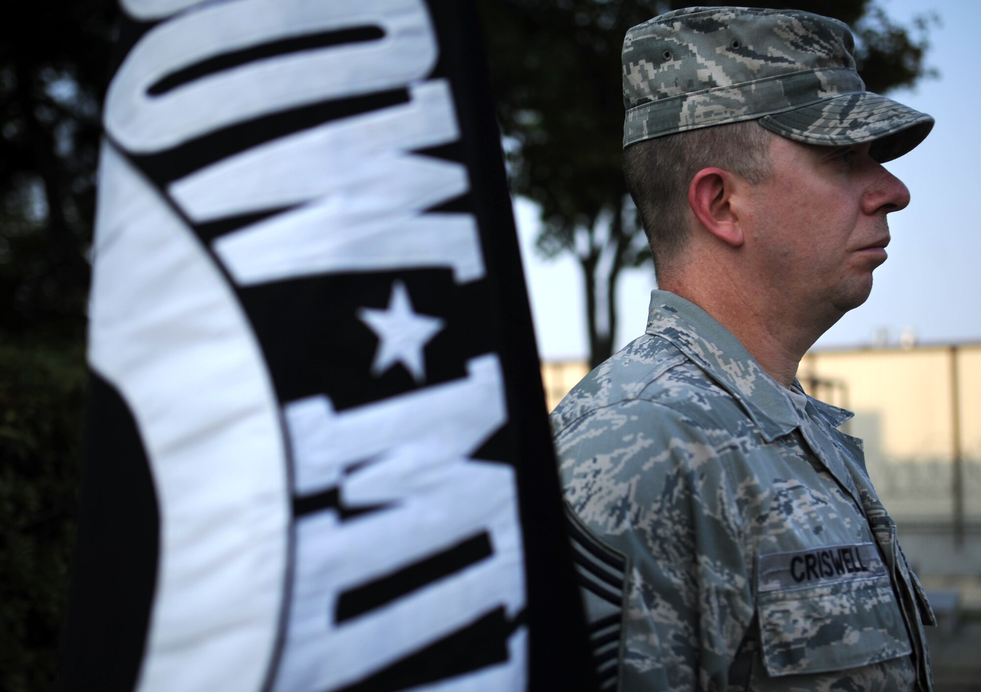 Chief Master Sgt. Brendan Criswell, 51st Fighter Wing command chief, stands next to the Prisoner of War/Missing in Action flag during a retreat ceremony to honor National POW/MIA Recognition Day at Osan Air Base, Republic of Korea, Sept. 18, 2013. Every year, National POW/MIA Recognition Day is observed on the third Friday in September to honor those who were prisoners of war and those who are still missing in action. (U.S. Air Force photo/Staff Sgt. Sara Csurilla)