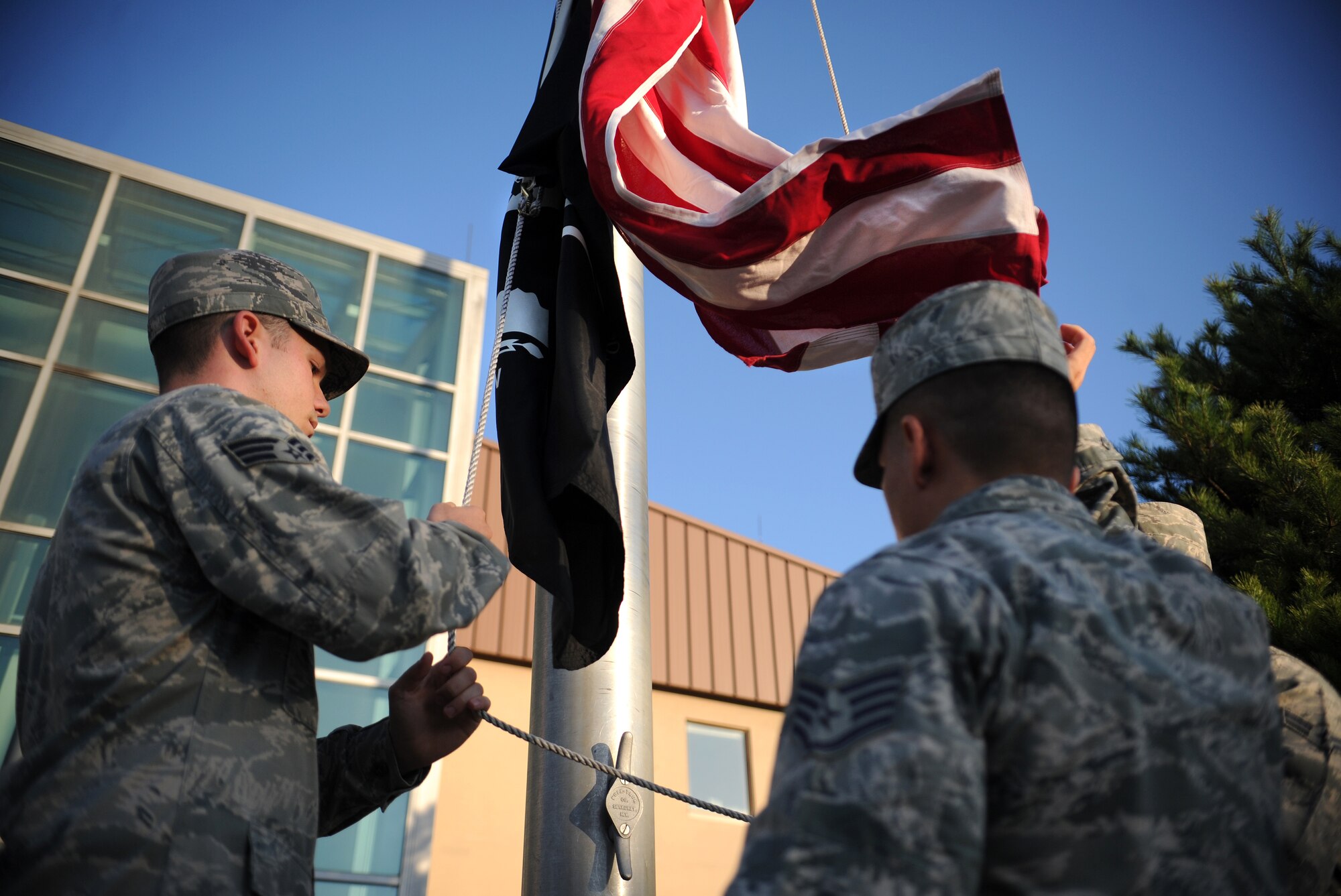 Osan Honor Guardsmen raise the American and Prisoner of War/Missing in Action flags during a reveille ceremony to kick off POW/MIA week at Osan Air Base, Republic of Korea, Sept. 17, 2013. An act of Congress established National POW/MIA Recognition Day by the passage of Section 1082 of the 1998 Defense Authorization Act. (U.S. Air Force photo/Staff Sgt. Sara Csurilla)