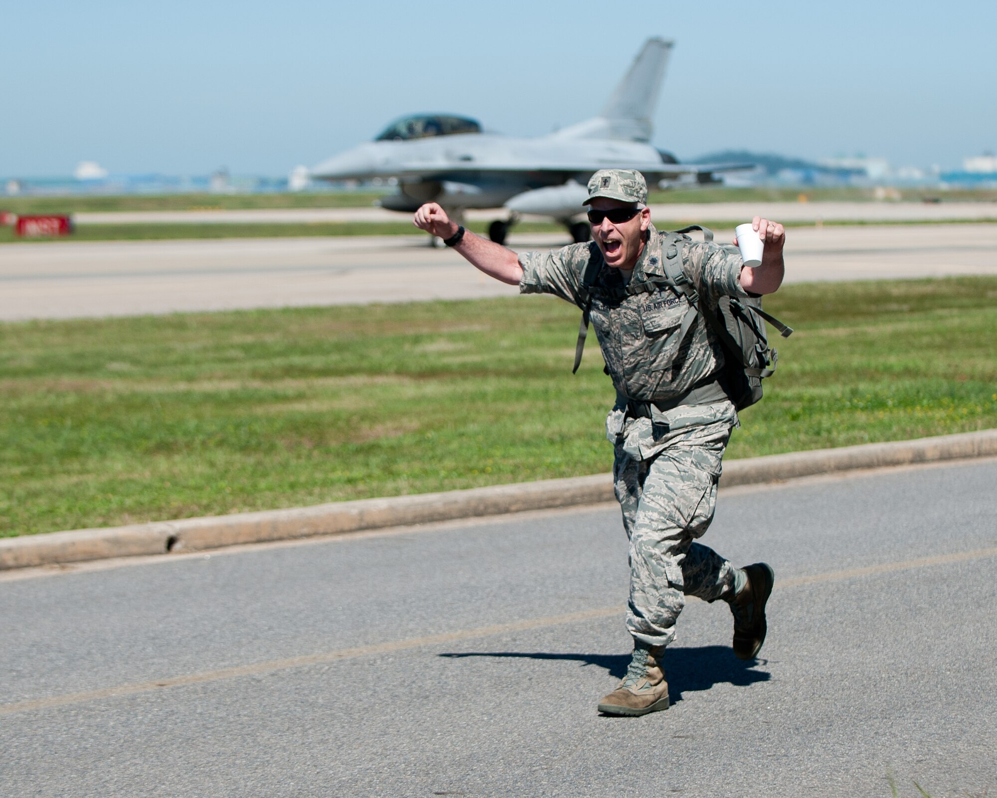 Lt. Col. Bryan Hochhalter, 8th Fighter Wing chaplain, celebrates his way across the finish line of the Kunsan Prisoner of War and Missing In Action Ruck March at Kunsan Air Base, Republic of Korea, Sept. 16, 2013. Hochhalter and the rest of participants marched a 5-mile course around the base to begin the Wolf Pack’s observance of prisoners of war and those missing in action. (U.S. Air Force photo by Senior Airman Clayton Lenhardt/Released)