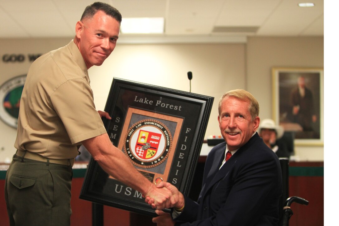 Lt. Col. Jan Durham, commanding officer of 1st Law Enforcement Battalion, presents a plaque of appreciation to Scott Voigts, mayor of Lake Forest. The city of Lake Forest voted unanimously to adopt 1st Law Enforcement Battalion in Lake Forest, Calif., Sept. 17.