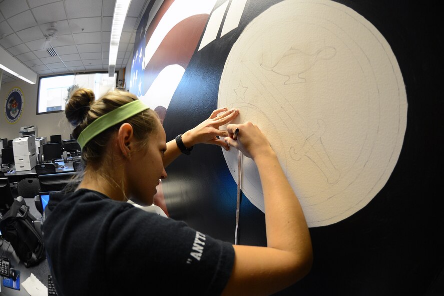 Senior Airman Skye Vicchio, 627th Logistics Readiness Squadron war reserve materiel manager, draws the border of the Air Education and Training Command emblem, Sept. 10, 2013, at Joint Base Lewis-McChord, Wash. The emblem is part of a mural she and two other Airmen are drawing for the Julius A. Kolb Airman Leadership School’s learning resource center. (U. S. Air Force photo/ Airman 1st Class Jacob Jimenez) 