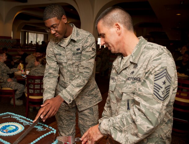 Chief Master Sgt. Steven Cleveland, 99th Air Base Wing command chief, and Airman 1st Class Timothy Tipton, 99th Communication Squadron wing information assurance officer, cut an Air Force 66th birthday cake at the Crosswinds Dining Facility Sept. 18, 2013, at Nellis Air Force Base, Nev. The two youngest Airmen in the dining facility were asked to join two most senior ranking members of the 99th ABW to cut the cake. (U.S. Air Force photo by Staff Sgt. Michael Charles)