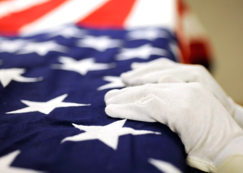 Staff Sgt. Jade Hunter, 28th Force Support Squadron mortuary affairs NCO in-charge, smoothes out a U.S. flag over a transfer case during a training session at Ellsworth Air Force Base, S.D., Aug. 16, 2013. From making sure the dress and uniform look the sharpest to ensuring the flag is properly placed over the casket, Hunter gurantees that every detail is attended to and that the proper honors are issued to those Airmen who have given the ultimate sacrifice. (U.S. Air Force photo by Airman 1st Class Anania Tekurio/Released)