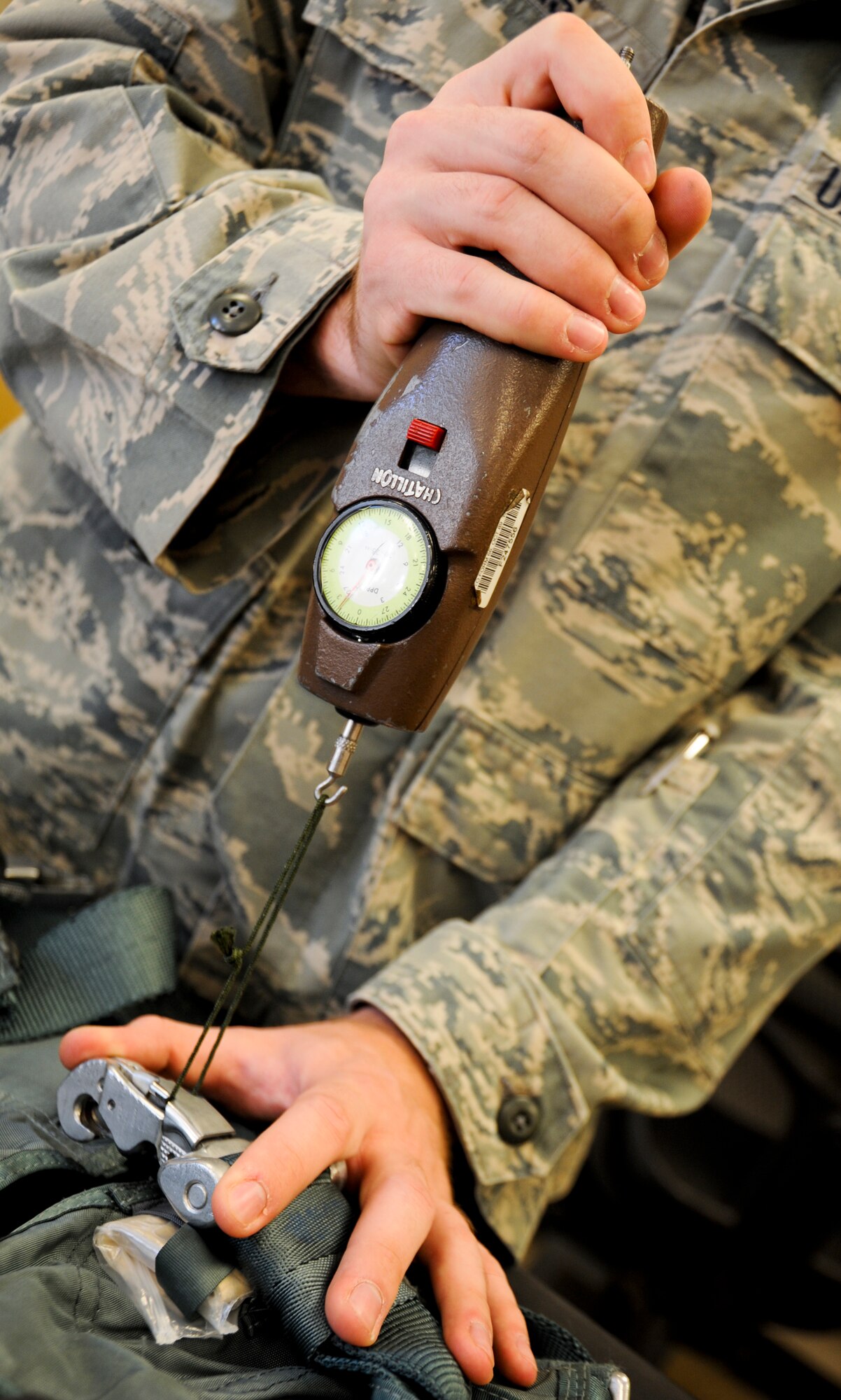 U.S. Air Force Airman 1st Class Kyle Rogers, 358th Fighter Squadron aircrew flight equipment apprentice, uses a push-pull gauge to test the ejector snaps on a PCU-15/p torso harness at Davis-Monthan Air Force Base, Ariz., Sept. 19, 2013. Aircrew Flight Equipment personnel issue, fit, repair, and maintain human-side flight equipment such as parachutes, helmets, oxygen equipment, anti-gravity garments, anti-exposure suits, aircrew ocular devices, survival kits, life preservers and other types of AFE. (U.S. Air Force photo by Airman 1st Class Justin Veazie/Released)