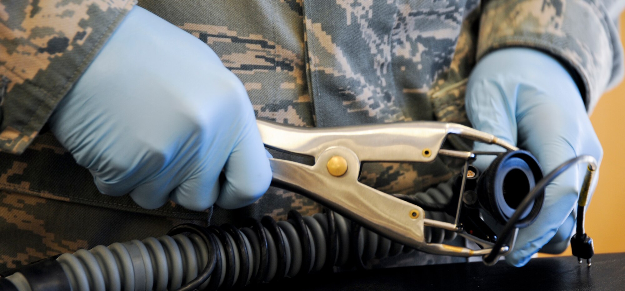U.S. Air Force Airman 1st Class Jose Padilla, 358th Fighter Squadron aircrew flight equipment apprentice, uses an elastrator as a safety precaution during his daily inspection at Davis-Monthan Air Force Base, Ariz., Sept. 19, 2013. The elastrator is used to expand the rubber so the Airman can inspect the rest of the tube without tearing the rubber. (U.S. Air Force photo by Airman 1st Class Justin Veazie/Released)