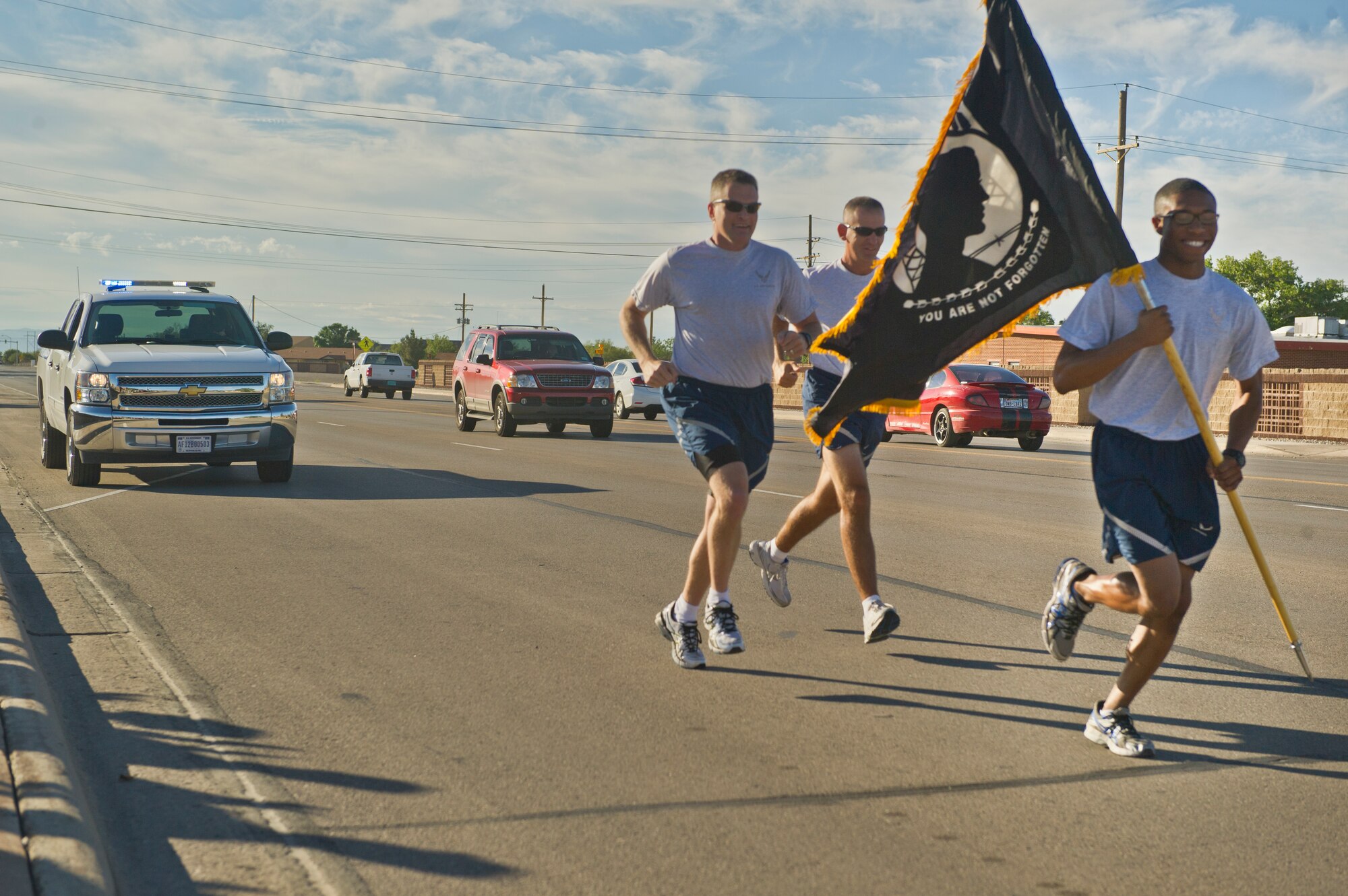 Colonel James Thompson, 49th Wing vice commander, 49th Wing Command Chief Master Sgt. James Patrie, and Airman 1st Class Michael Redford, 49th Wing Financial Analysis Technician, carry the POW/MIA flag as they start their run to the Domenici Sports and Fitness Center outdoor track during the annual POW/MIA Day of Remembrance at Holloman Air Force Base, N.M., Sept. 19. Members of Team Holloman paid their respects by taking shifts with the flag, running a total of 24 hours and always keeping the flag moving in honor of prisoners of war and service members missing in action. (U.S. Air Force photo by Airman 1st Class Chase Cannon/Released)