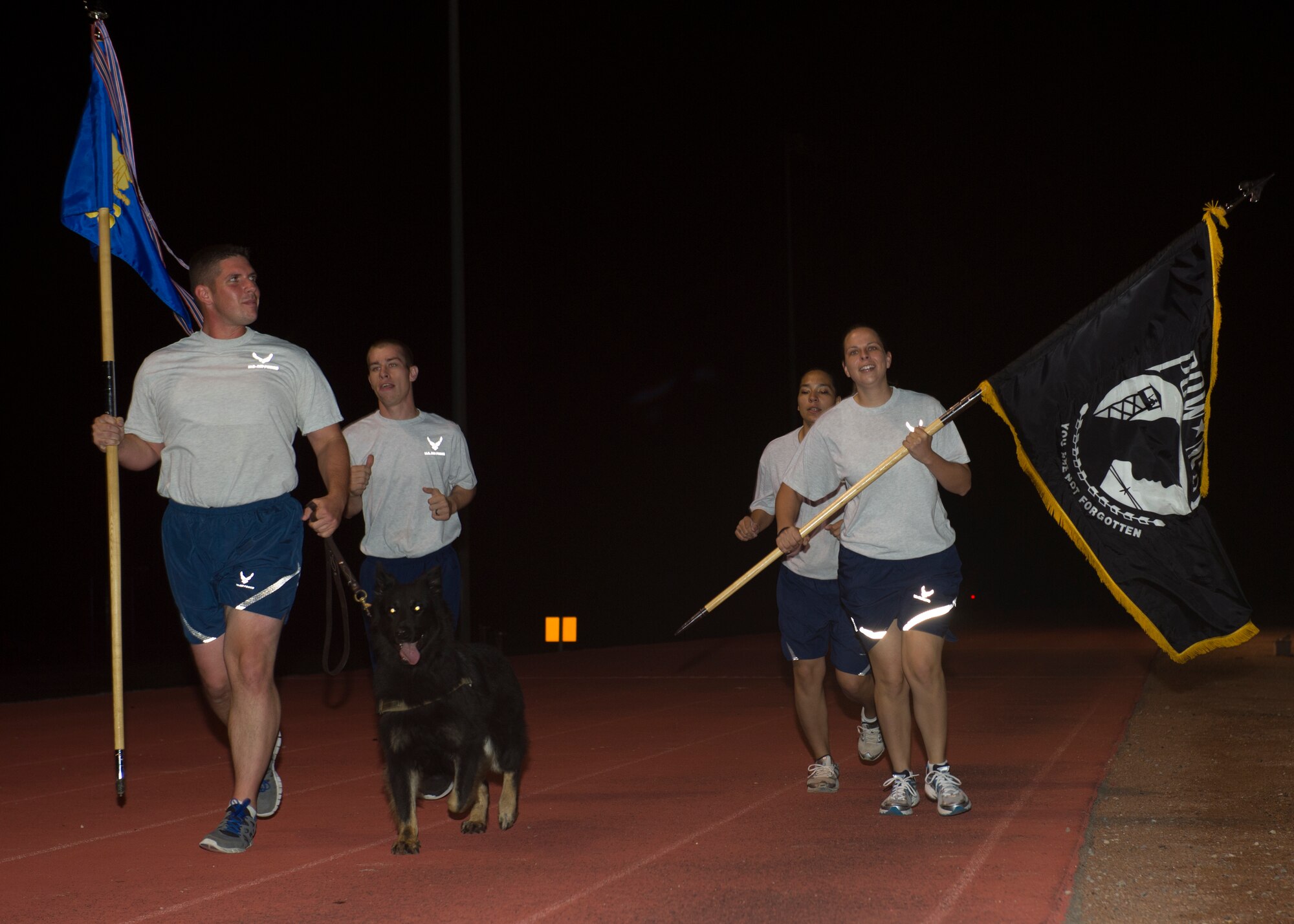 Members from the 49th Security Forces Squadron and Military Working Dog Luxi take their shift running the POW/MIA flag during the POW/MIA Day of Remembrance at Holloman Air Force Base, N.M., Sept. 19. Members of Team Holloman paid their respects by taking shifts with the flag, running a total of 24 hours and always keeping the flag moving in honor of prisoners of war and service members missing in action. (U.S. Air Force photo by Airman 1st Class Leah Murray/Released)